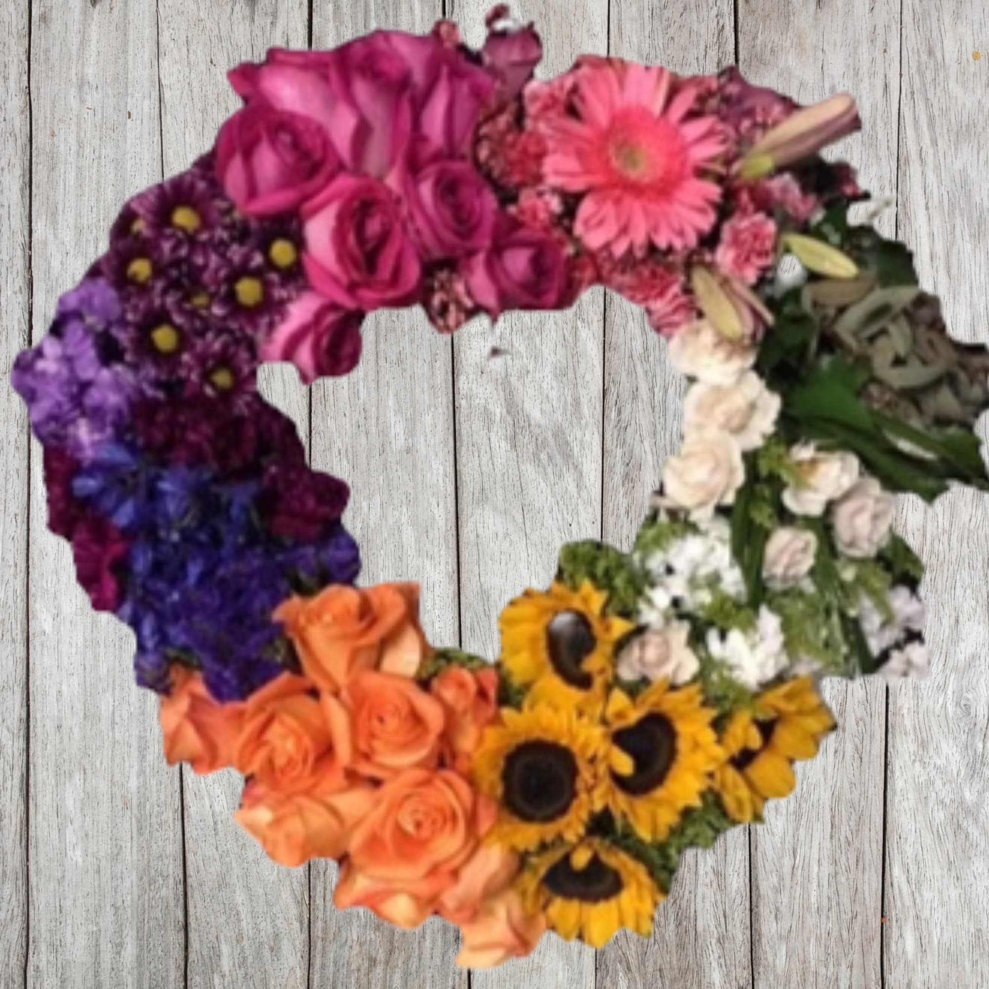 Heart-shaped floral wreath with multicolored flowers on a wood background