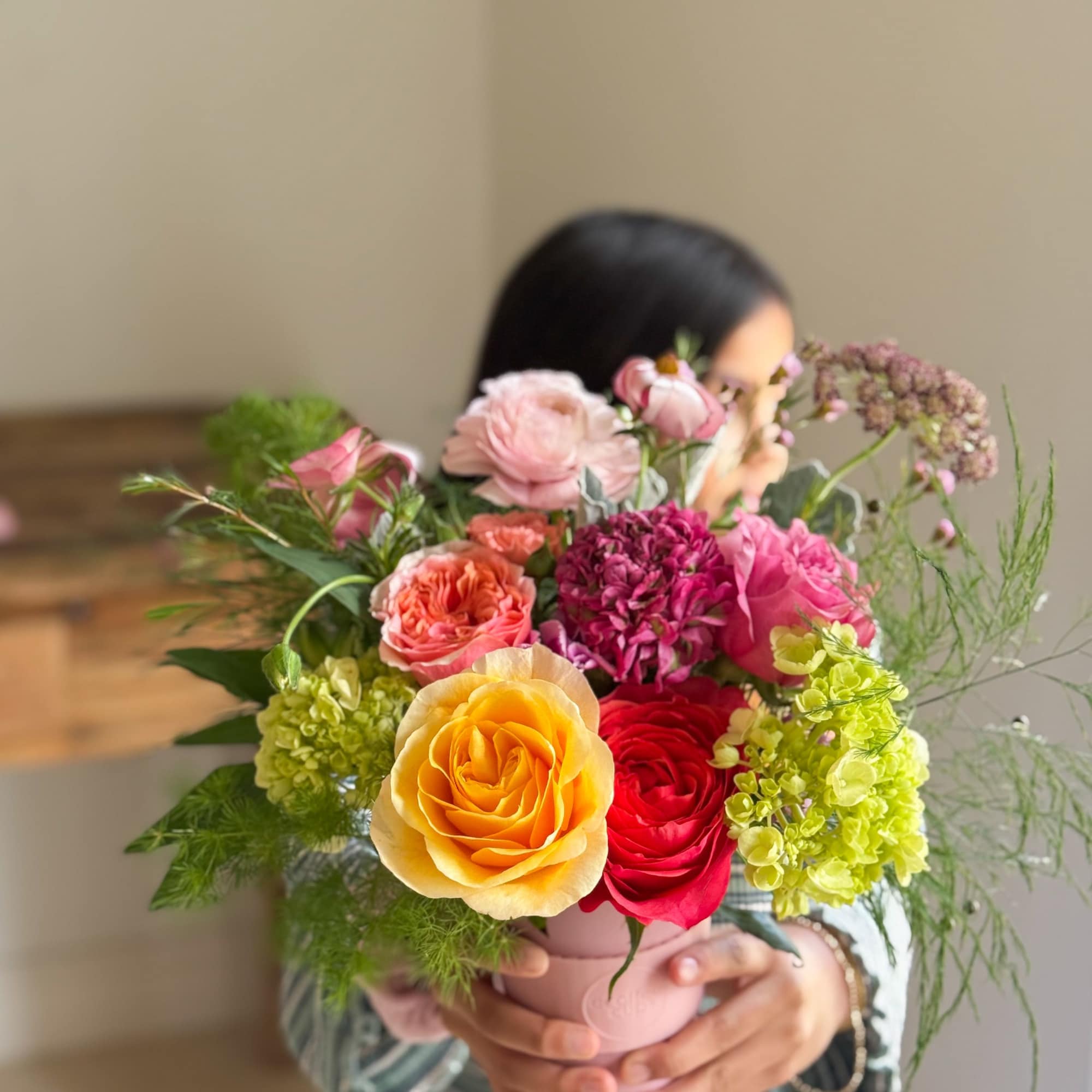 Colorful mixed bouquet in a pink vase held by a person