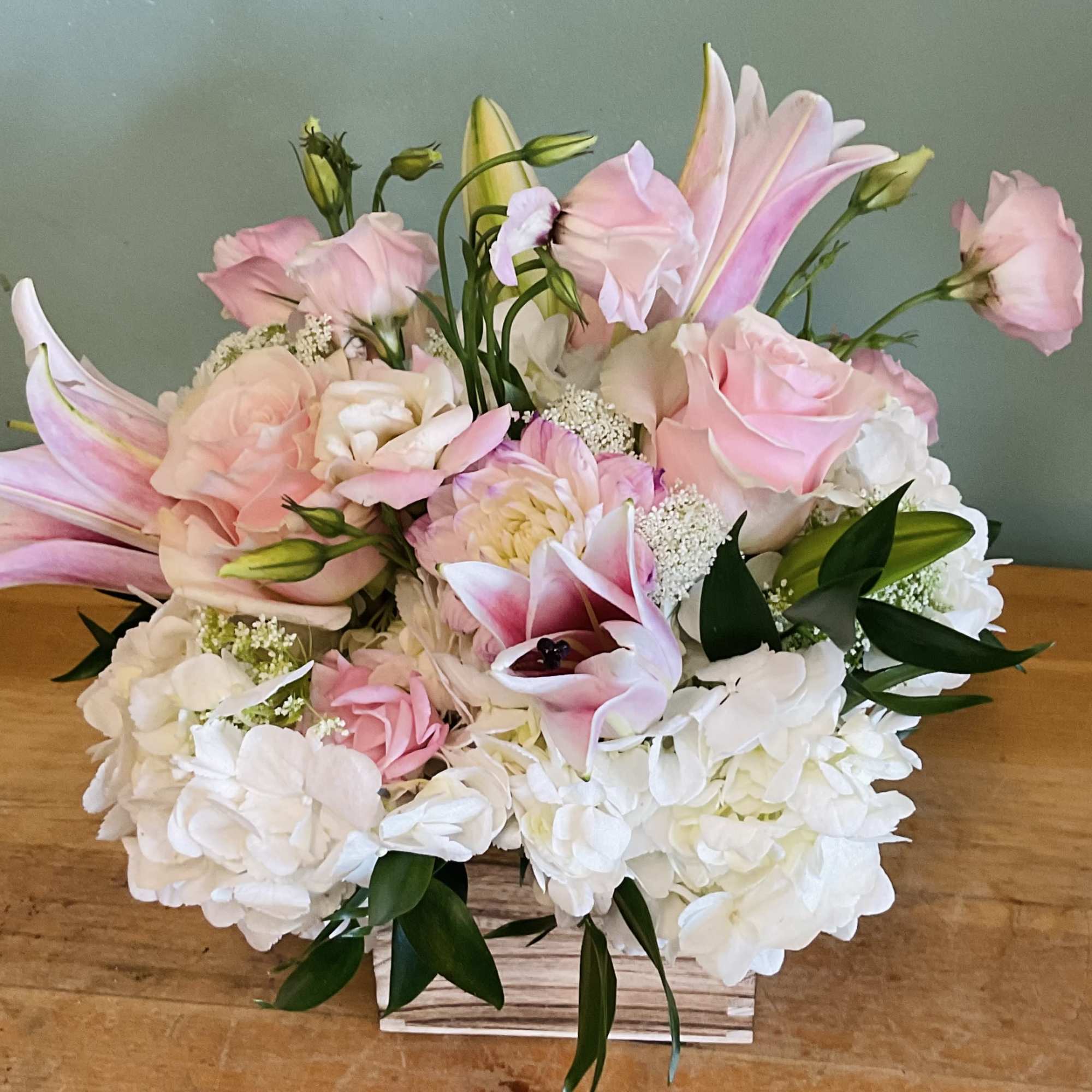 Soft pink lilies and roses mingle with creamy white hydrangeas and delicate
