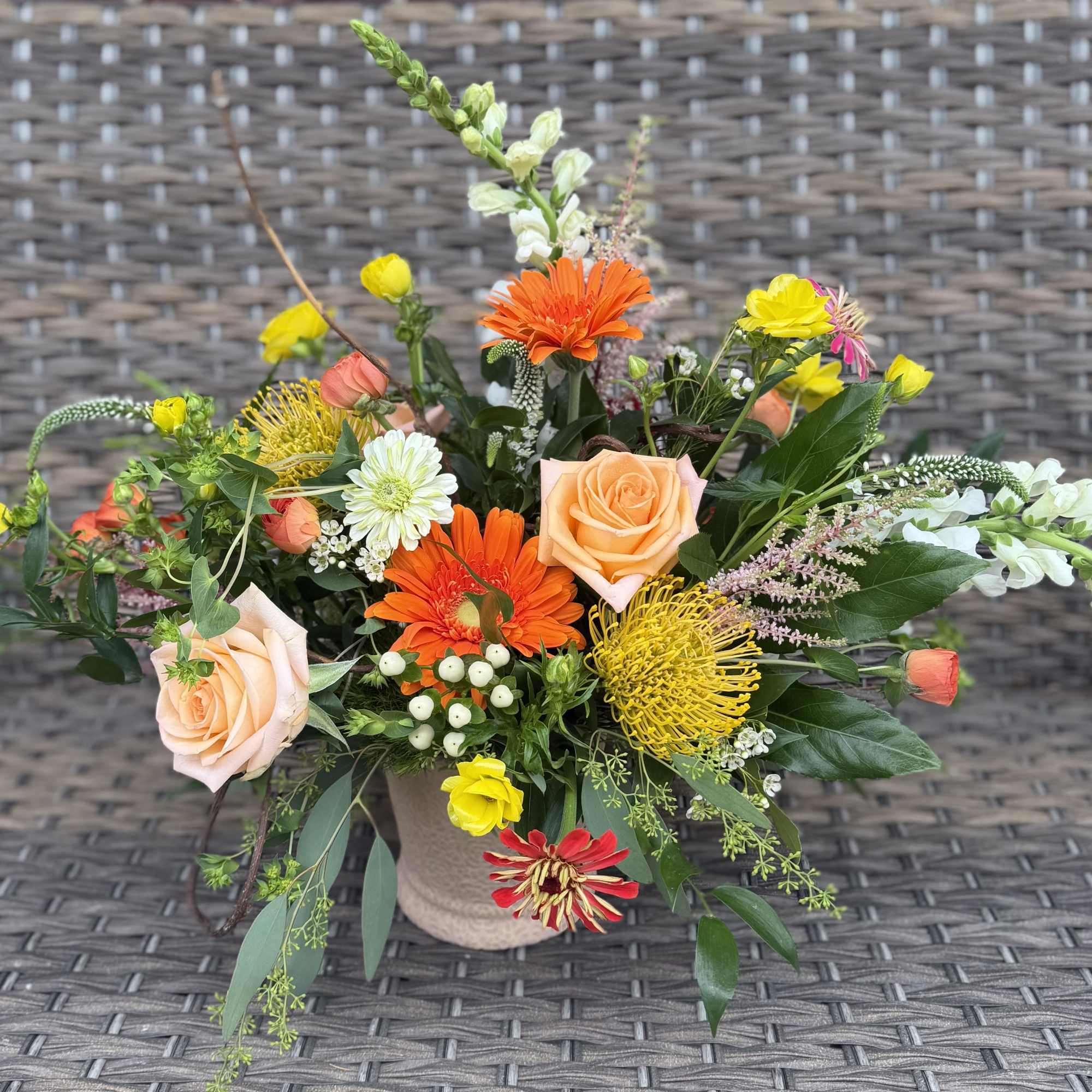This texture filled design in a ceramic pot showcases seasonal blooms. Flower
