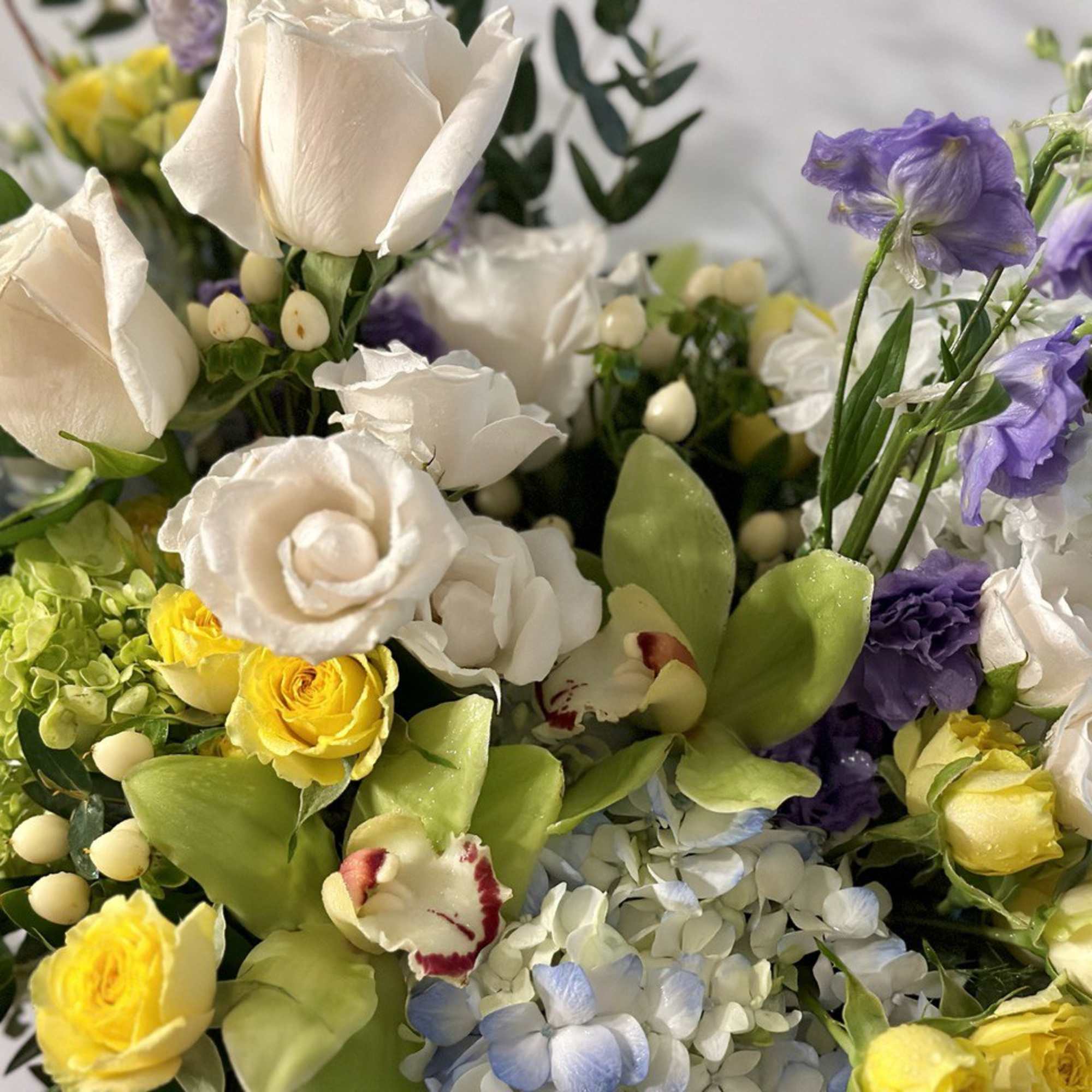 Bouquet of white roses, yellow blooms, and purple flowers
