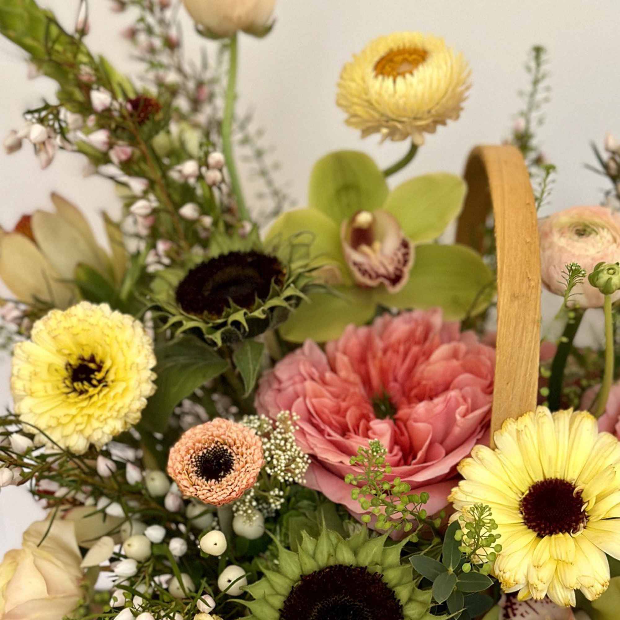 Basket of mixed flowers with sunflowers, pink blooms, and orchids