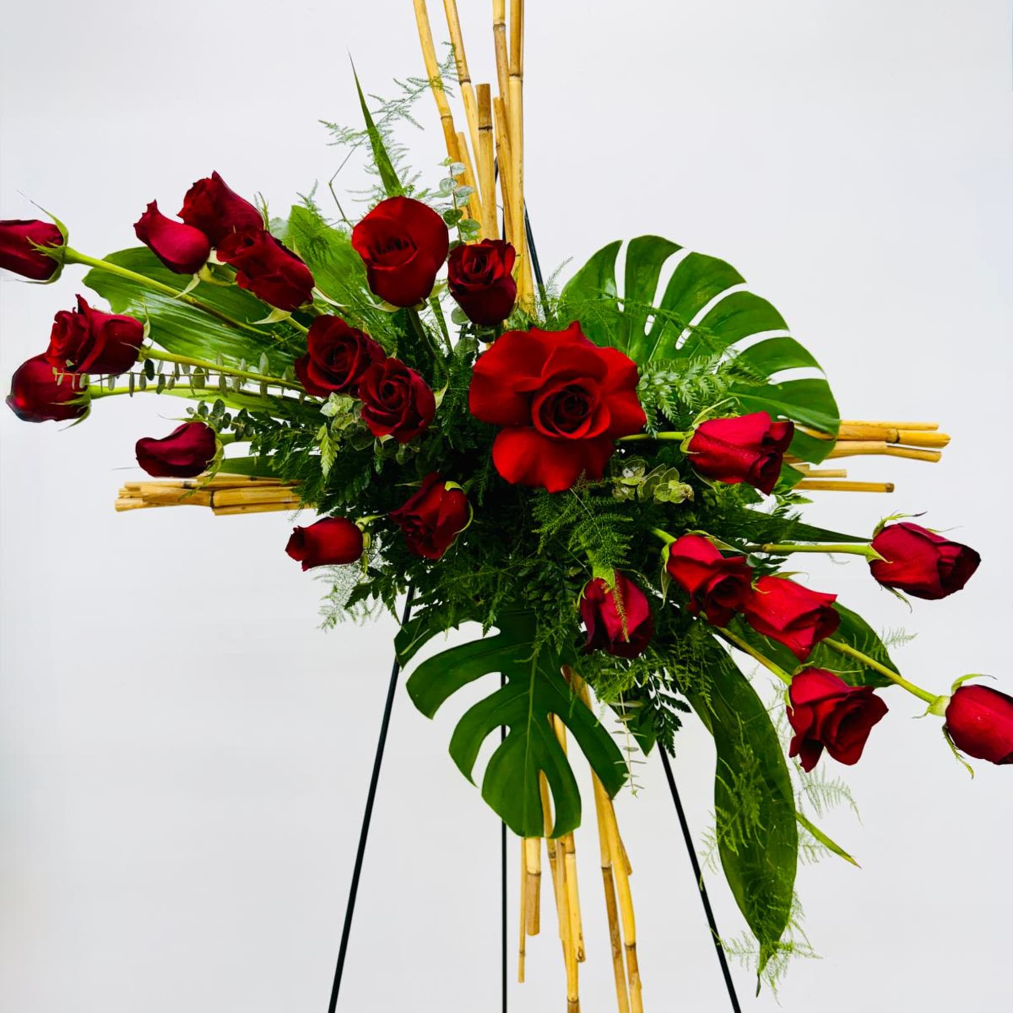 Red roses arranged with tropical leaves on a stand