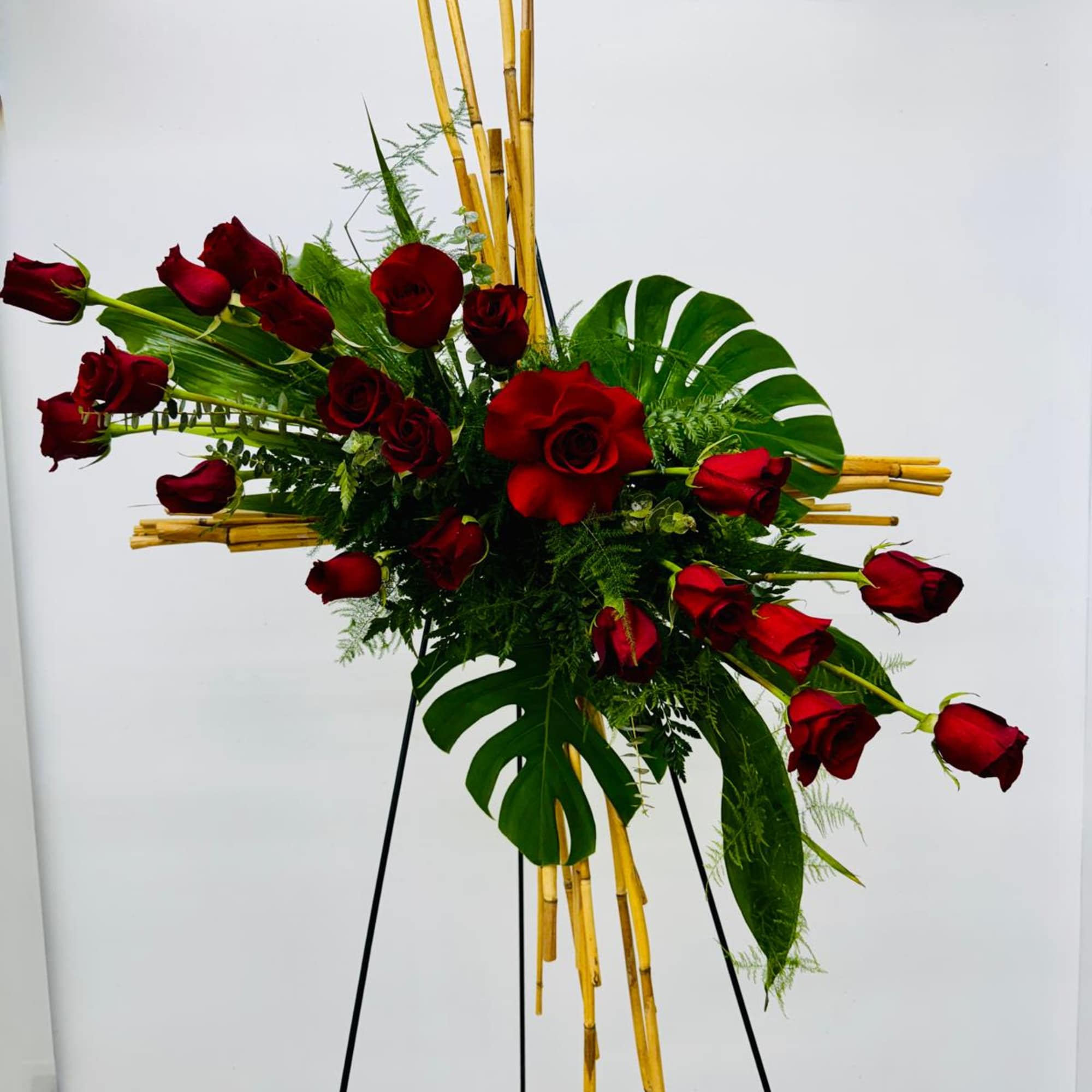 Red roses arranged with tropical leaves on a standing easel