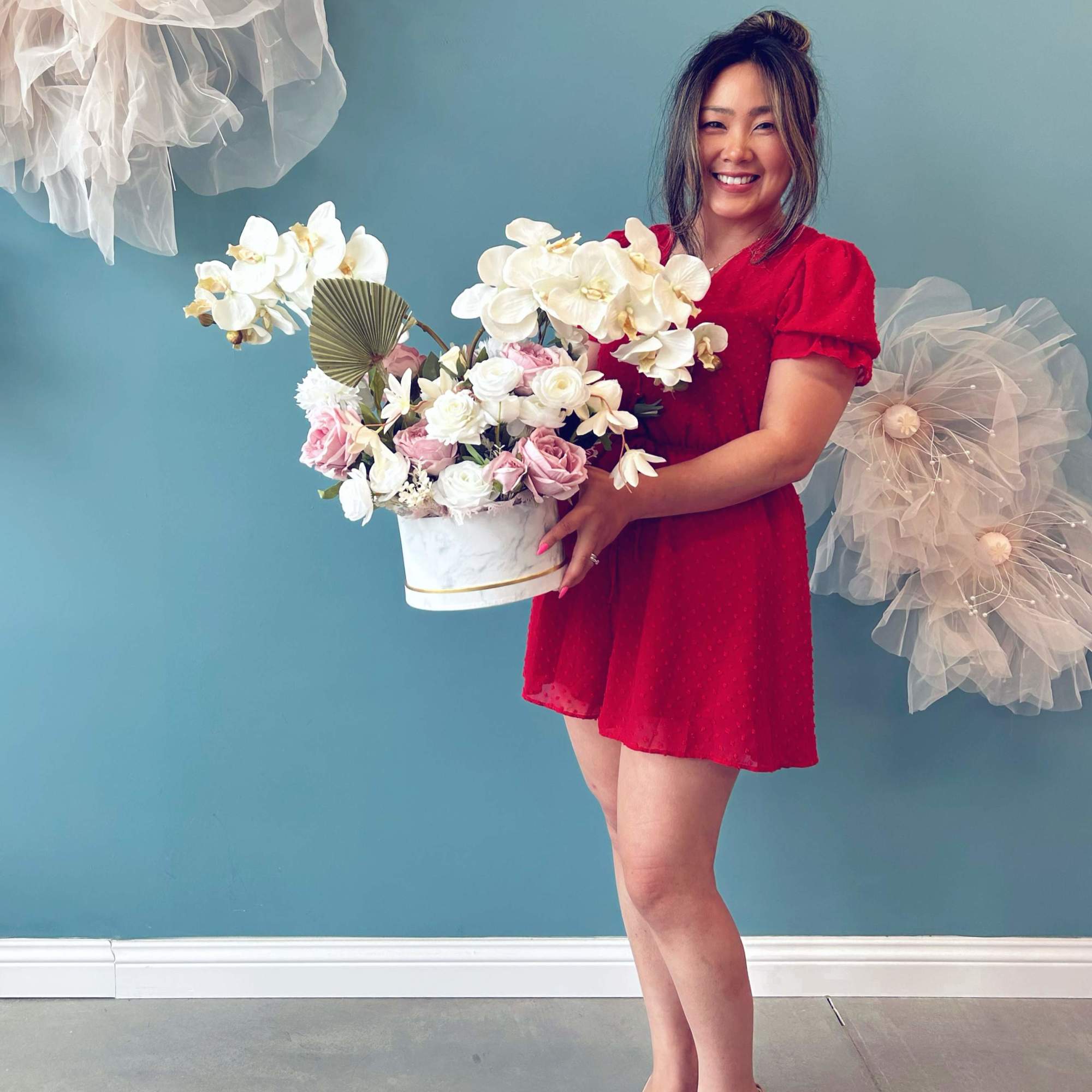 Woman holding a white hatbox arrangement of pink and white flowers