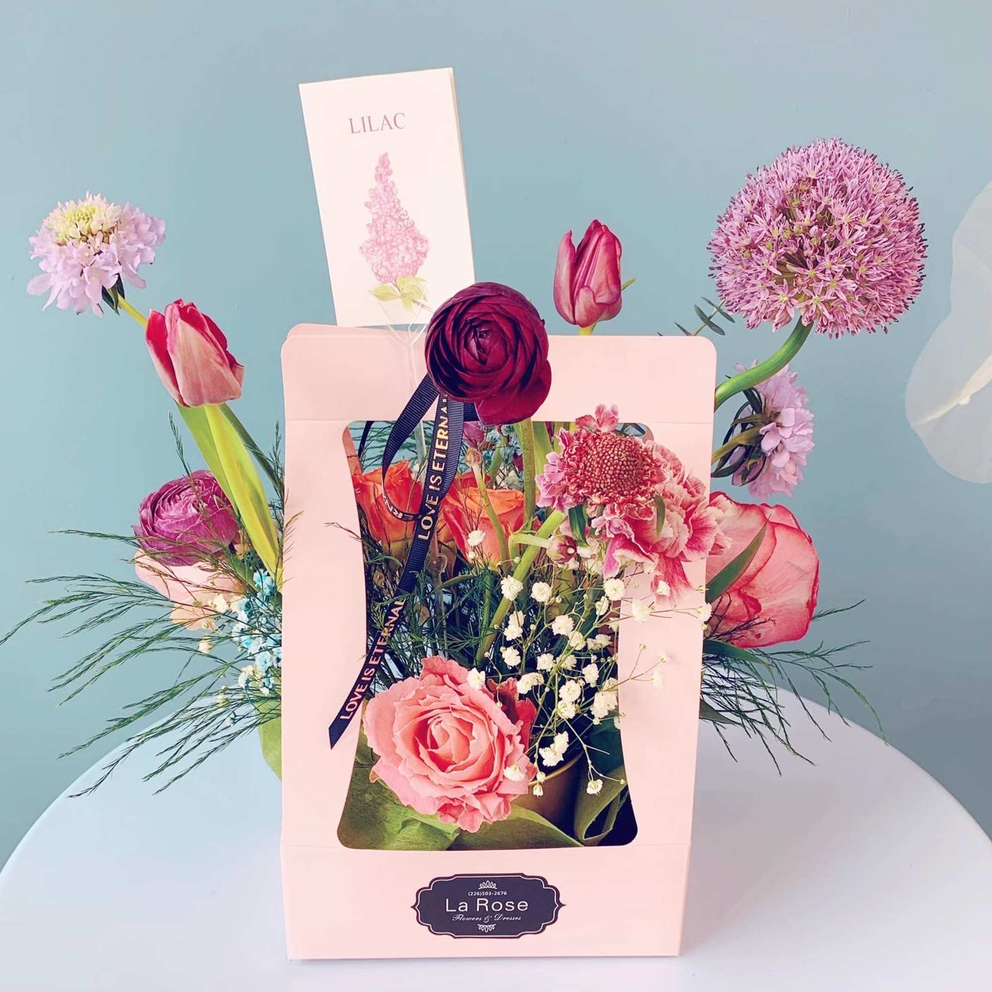 Pink and purple flower arrangement in a gift box with a ribbon