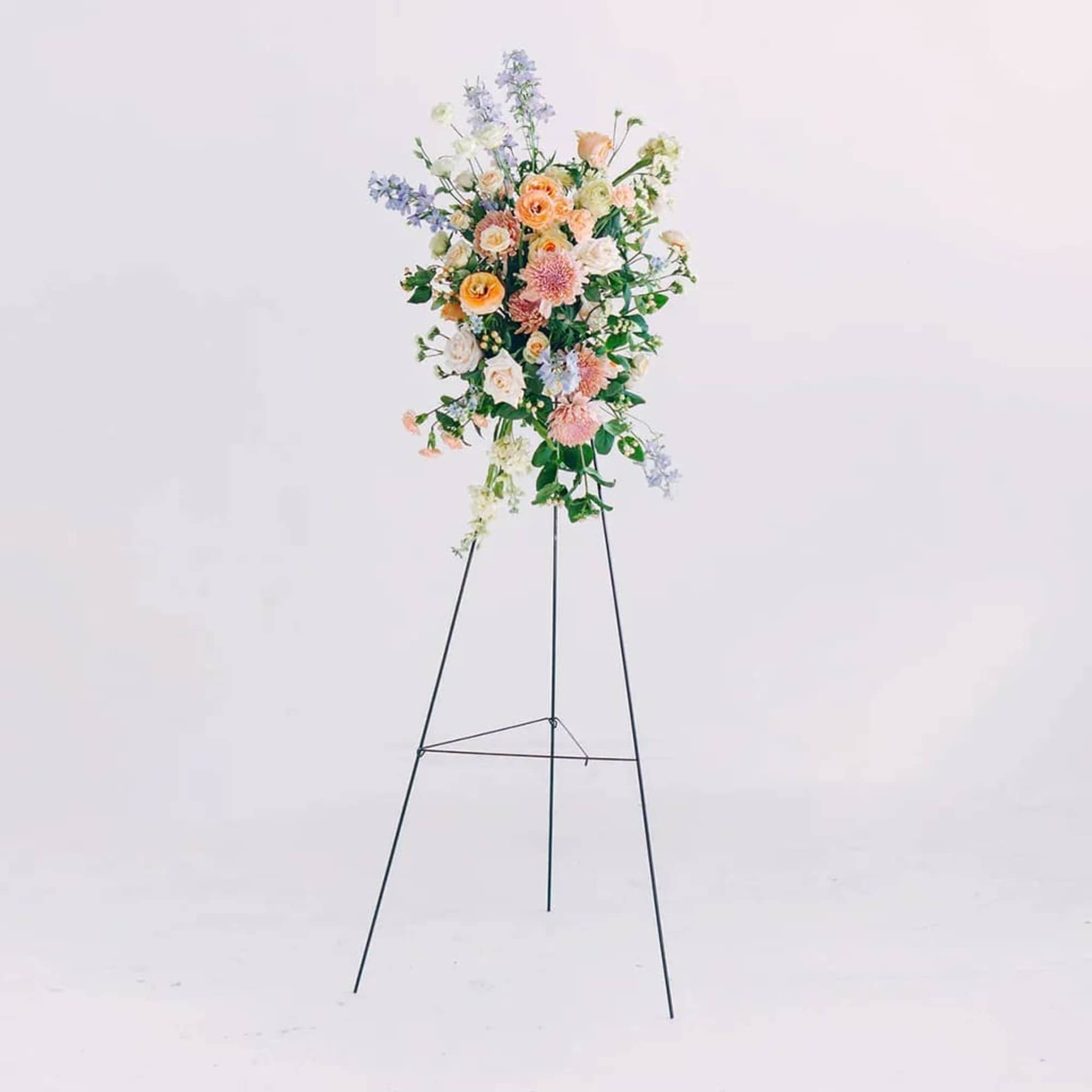 Tall pastel floral arrangement on a black metal stand