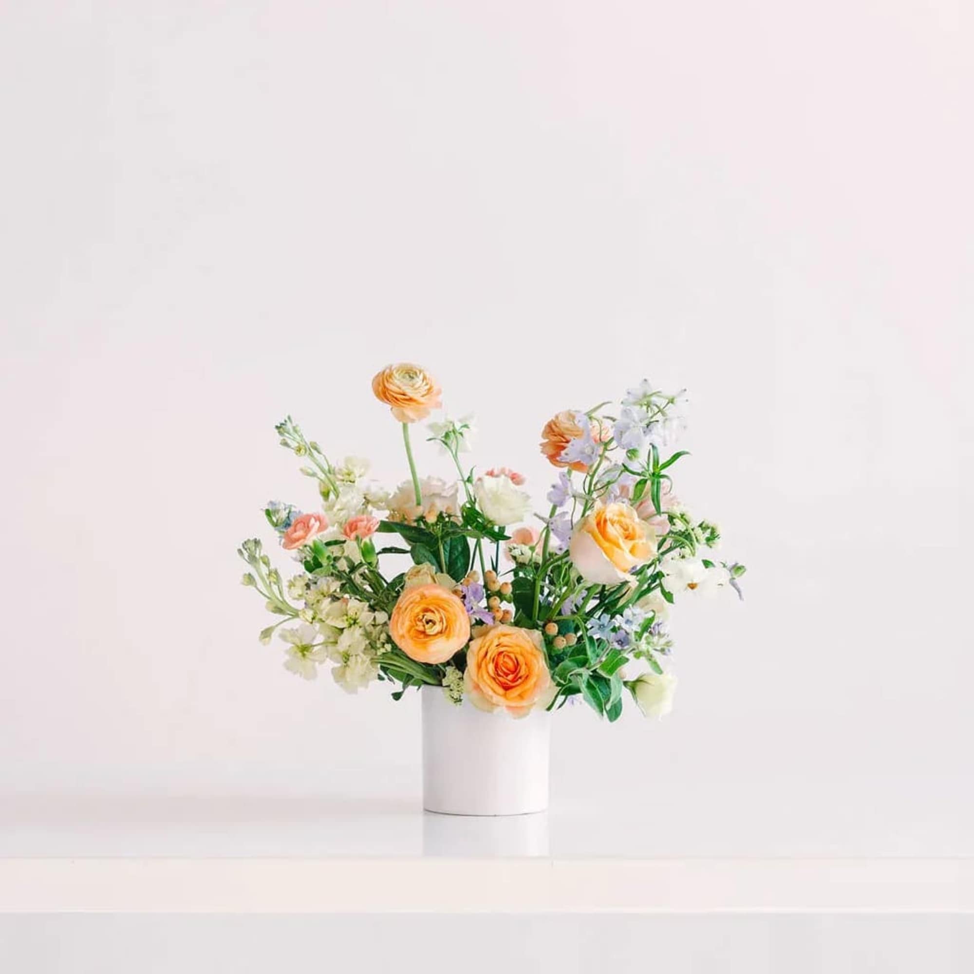 Peach and white floral arrangement in a white vase