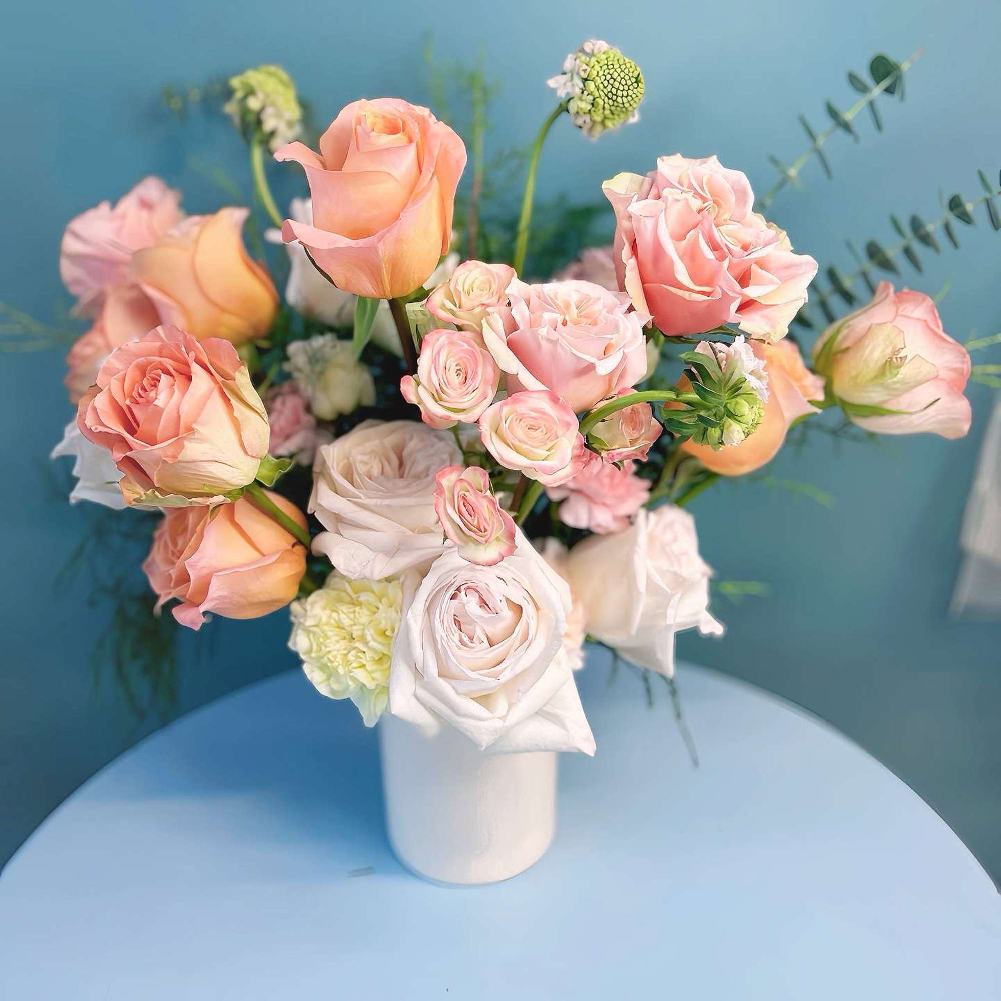 Peach and blush roses arranged in a white vase
