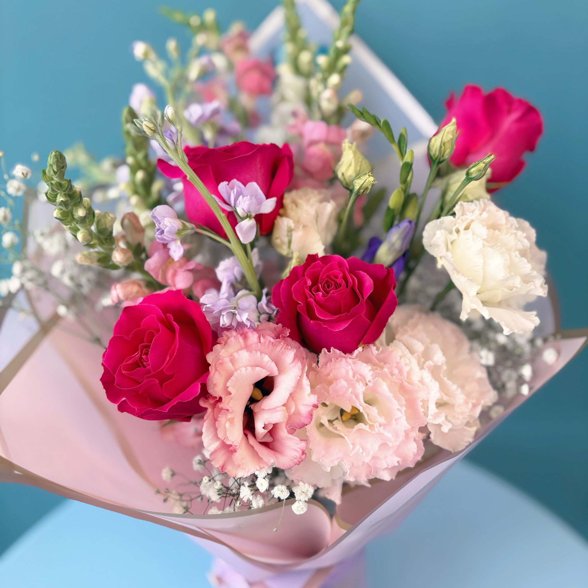 Bouquet of pink roses and pale lisianthus wrapped in pastel paper