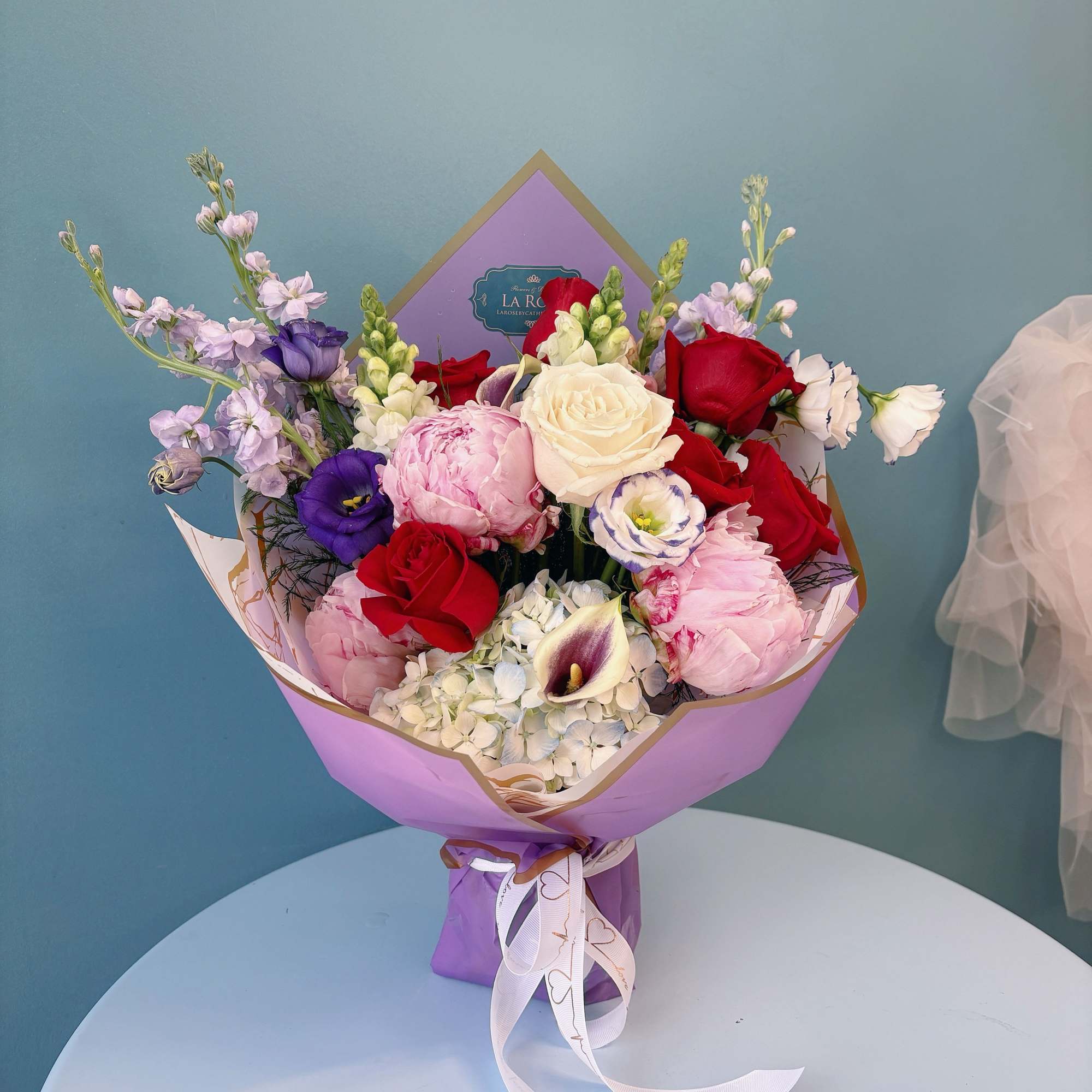 Bouquet of red, pink, white, and purple flowers wrapped in lavender paper