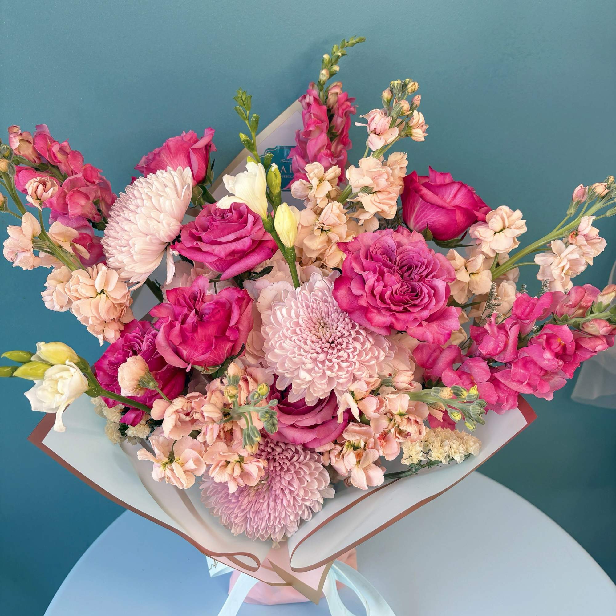 Bouquet of pink roses, chrysanthemums, and snapdragons wrapped in paper