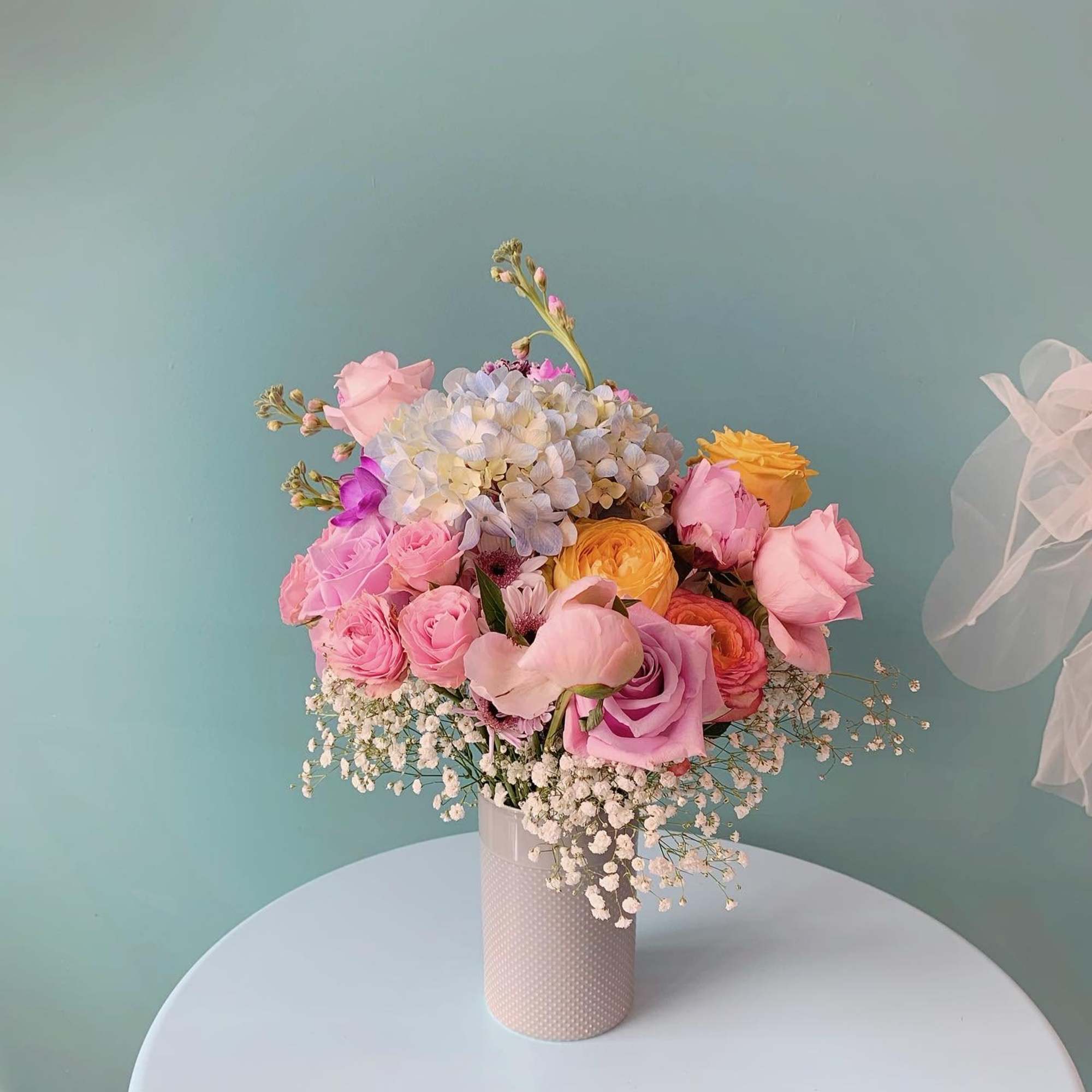 Pink and pastel mixed flower bouquet in a textured vase