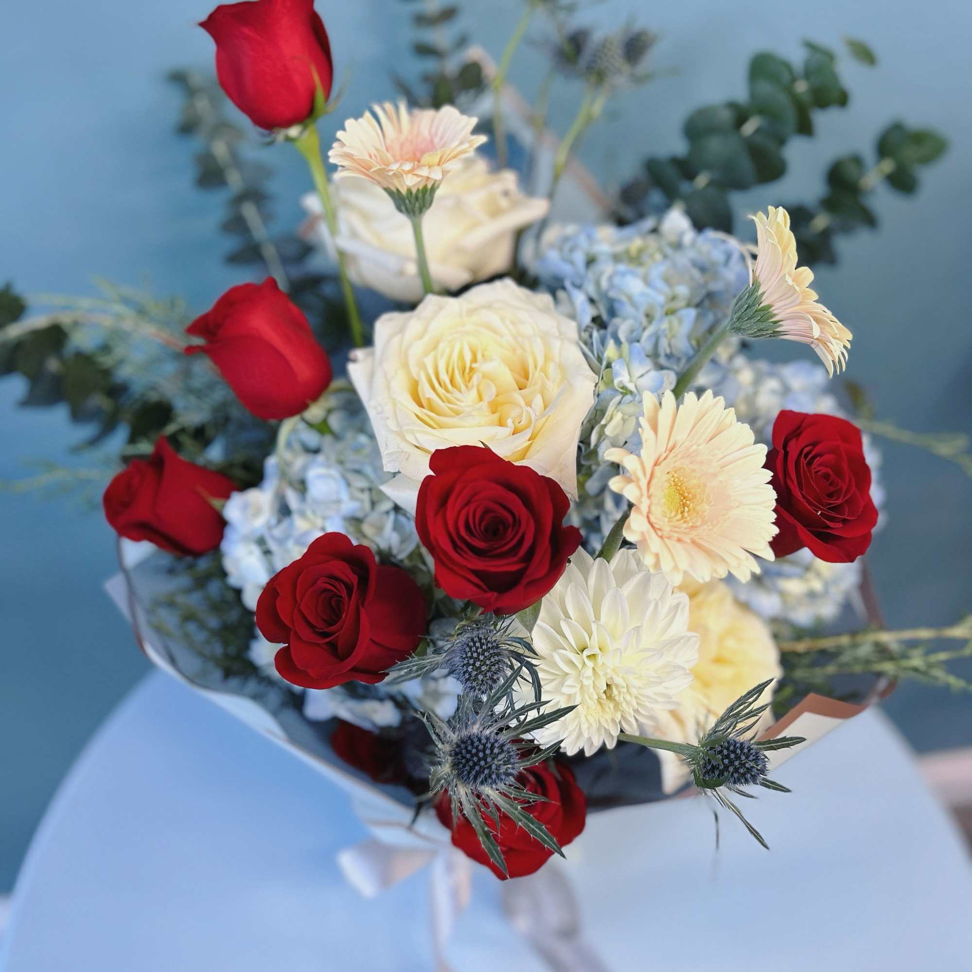 Bouquet of red and white roses with pale daisies and blue hydrangea