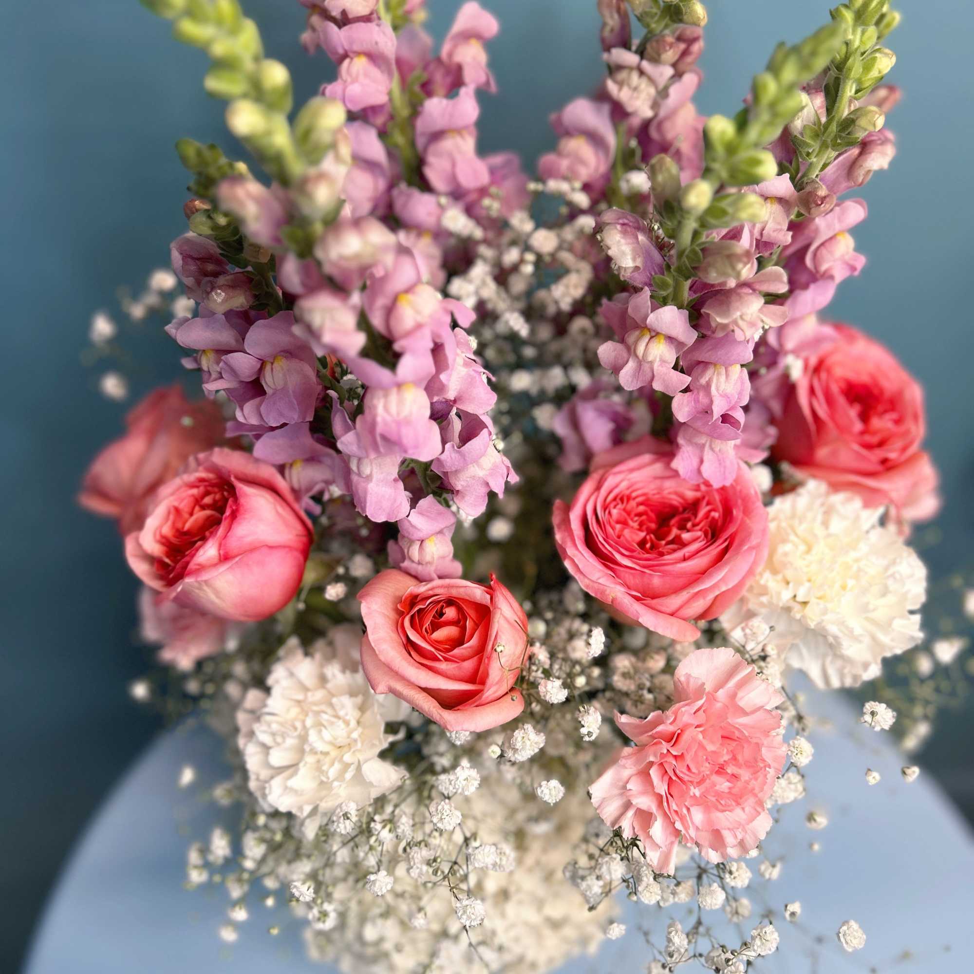 Pink roses, snapdragons, carnations, and baby's breath in a bouquet