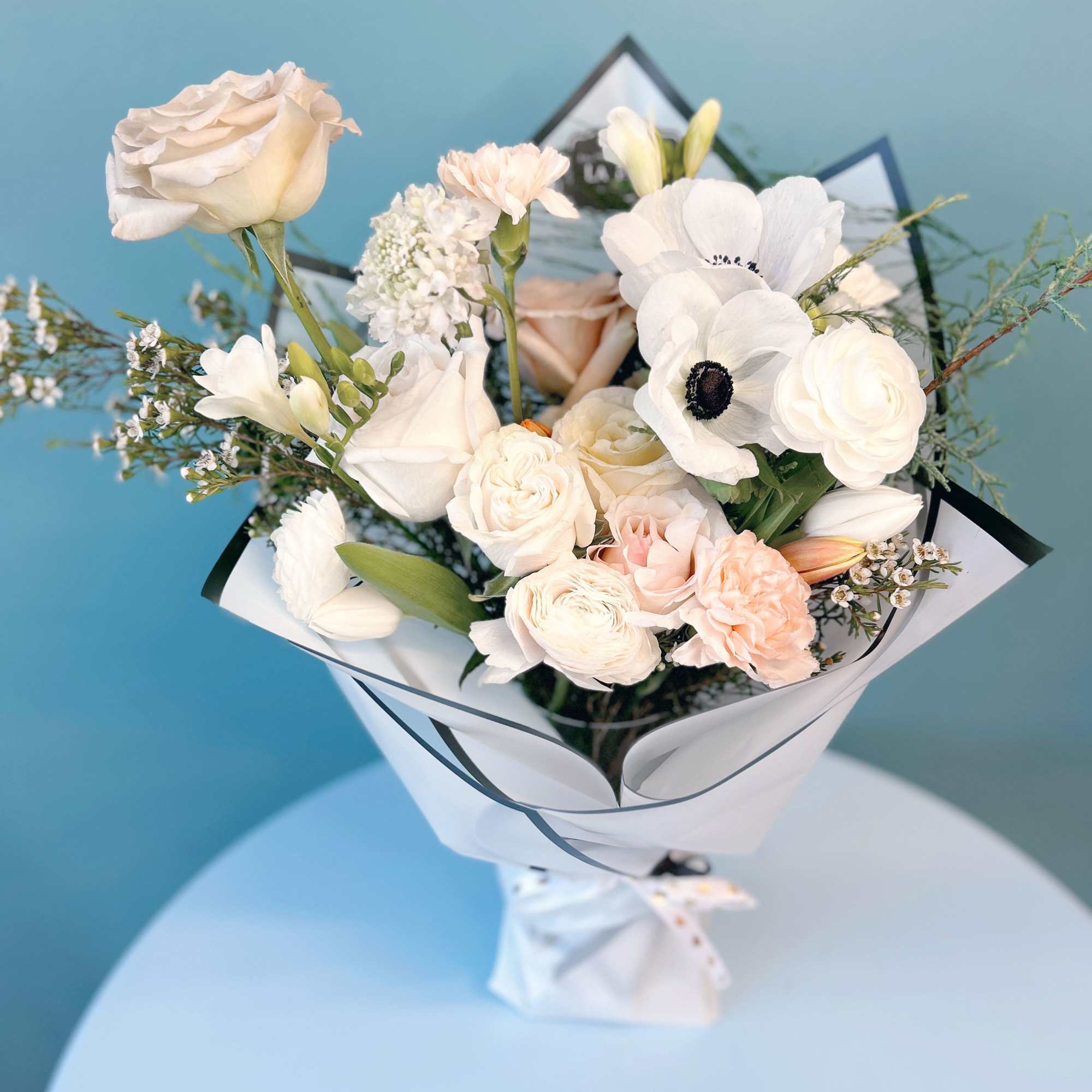Bouquet of white and blush flowers wrapped in white paper