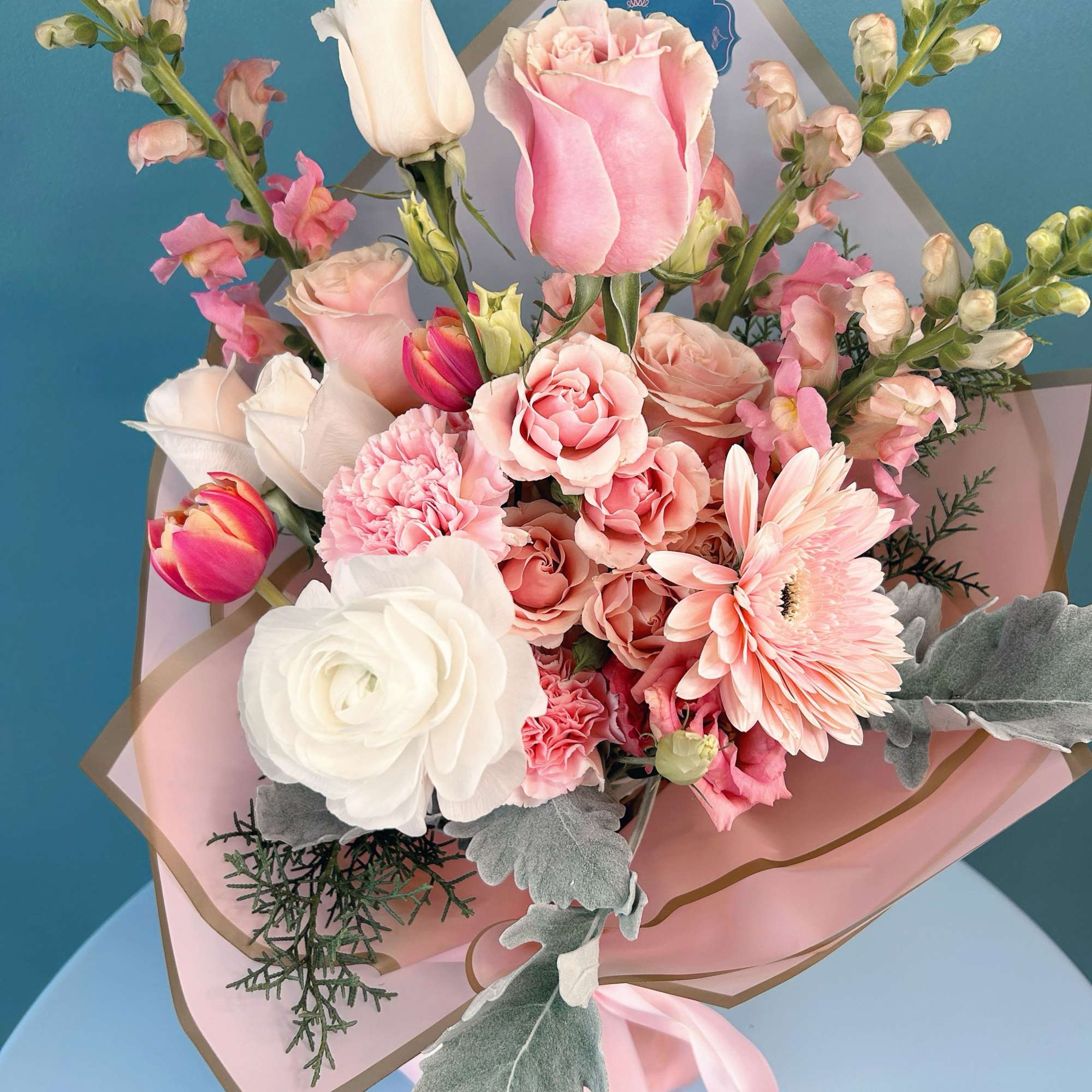 Pink and white bouquet with roses, carnations, tulips, and a gerbera daisy