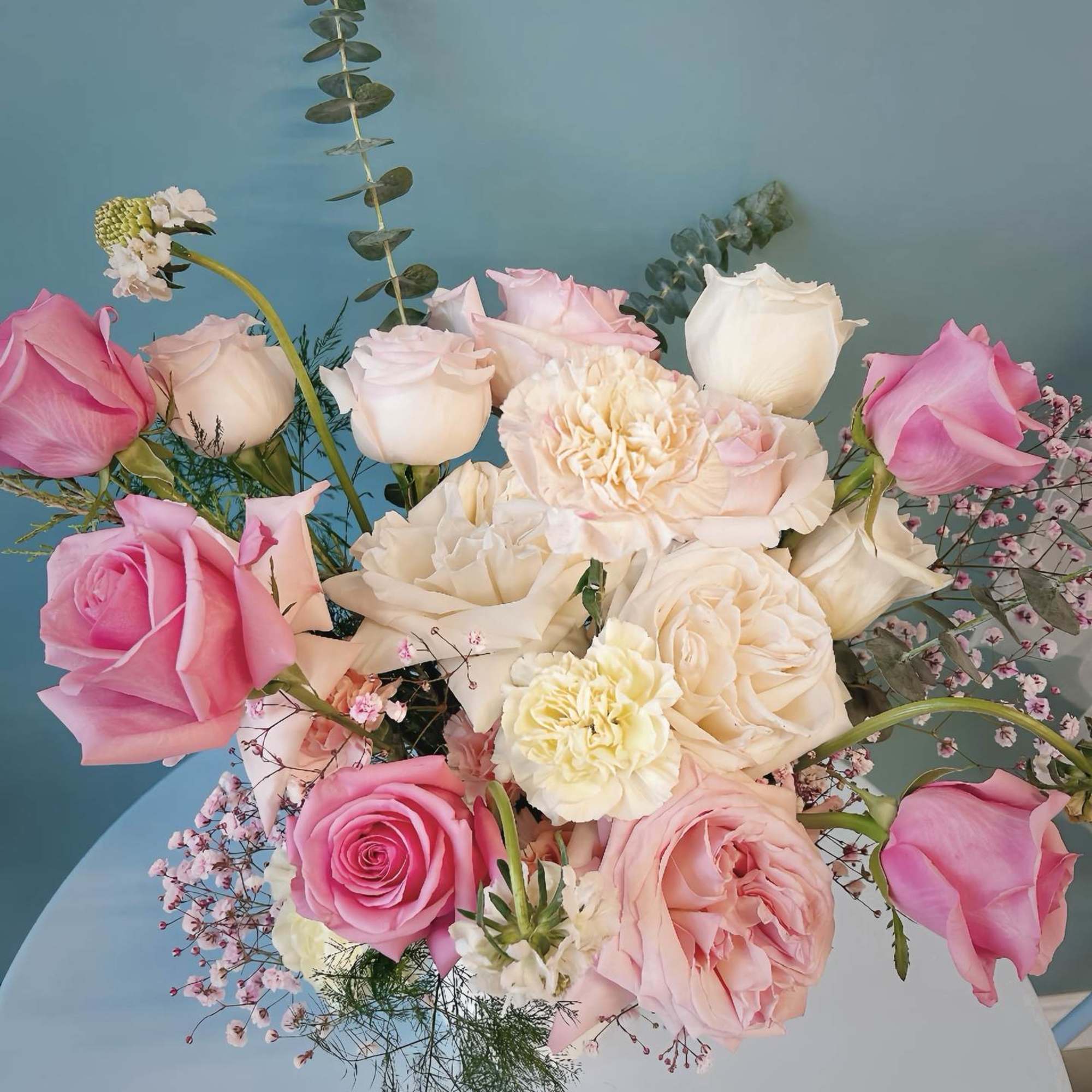 Bouquet of pink and white roses with carnations against a blue background