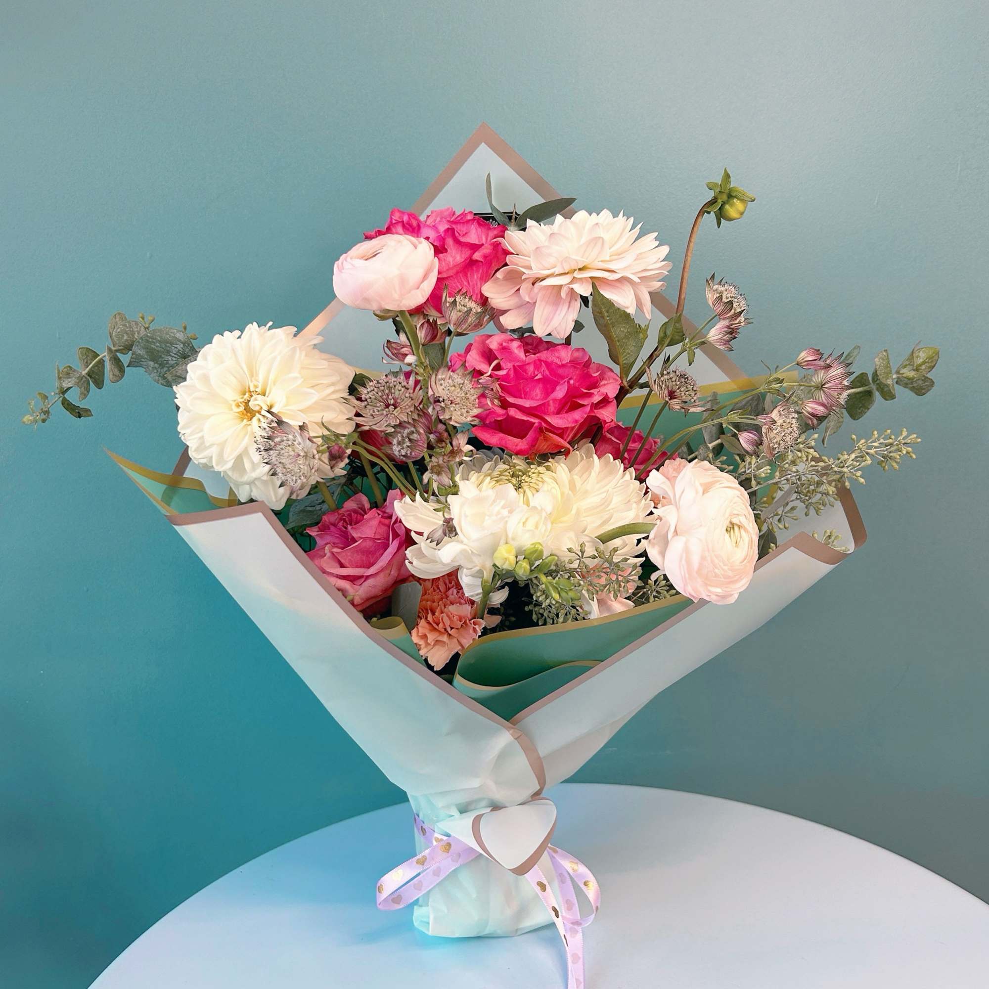 Bouquet of pink and white flowers wrapped in paper with a ribbon