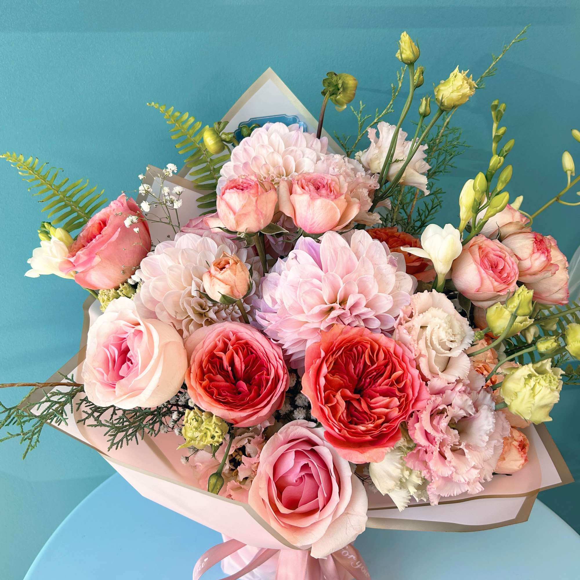Pink and peach bouquet with roses, dahlias, and lisianthus in paper wrap
