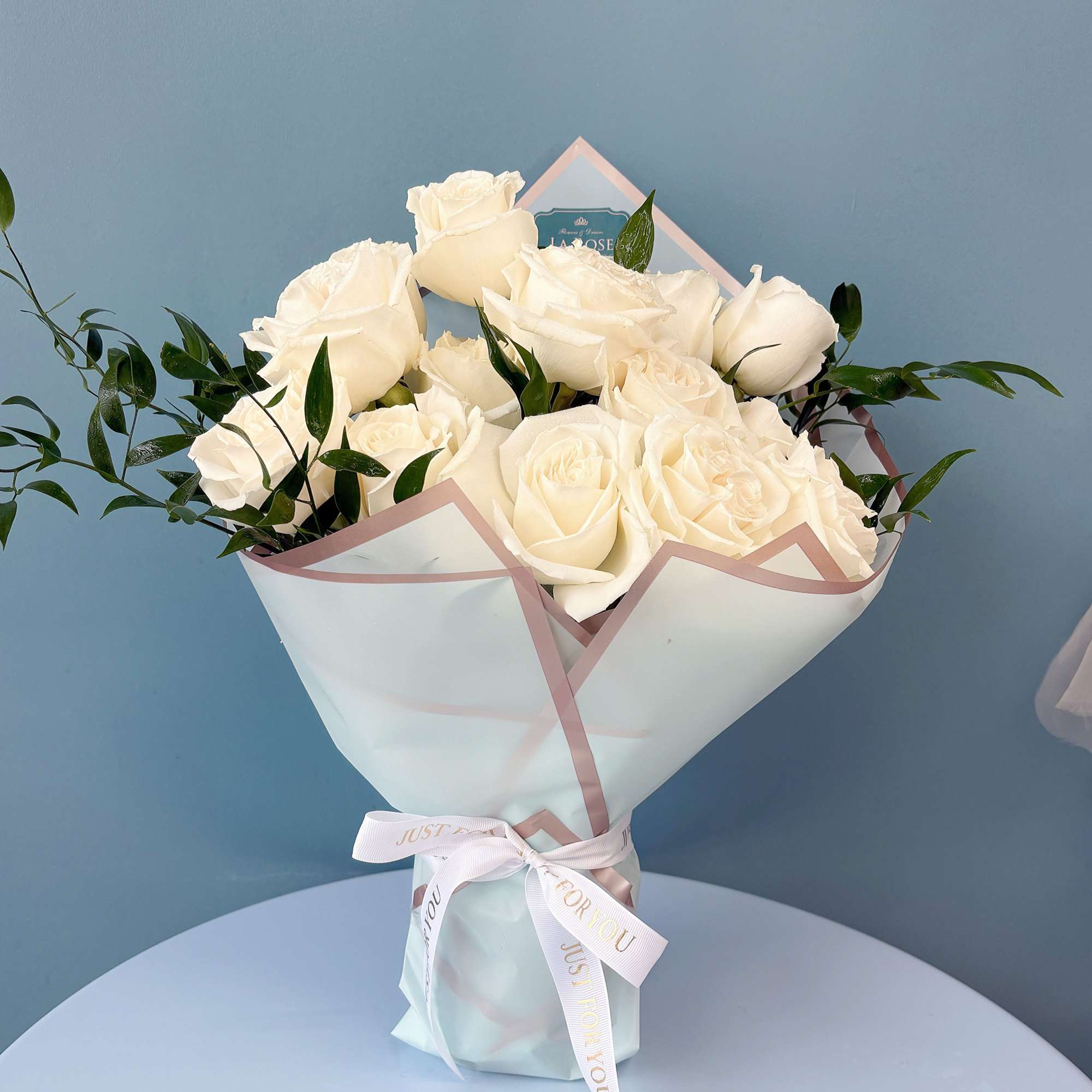Bouquet of white roses wrapped in pale paper with a ribbon