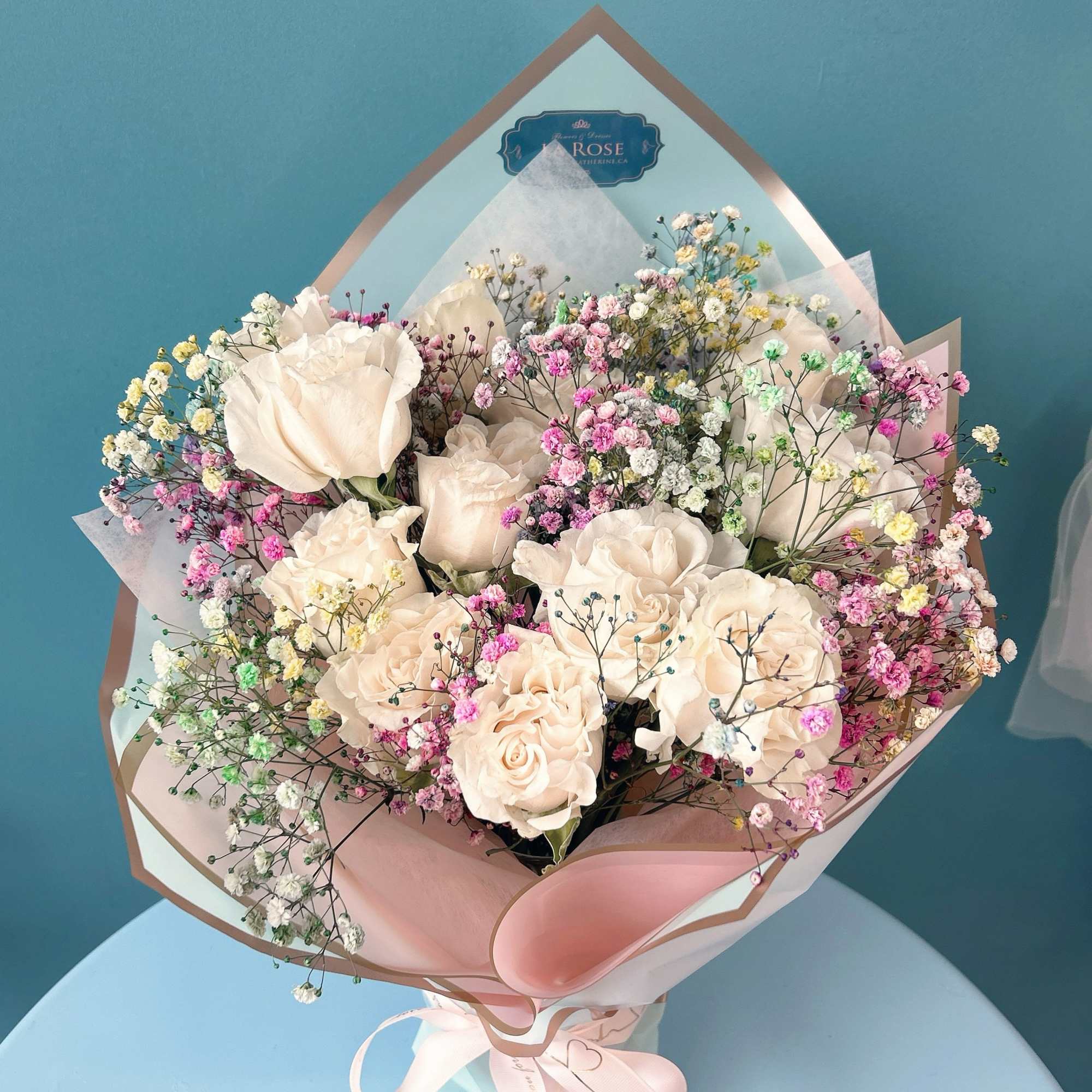 Bouquet of pale roses with colorful baby's breath in pink wrapping