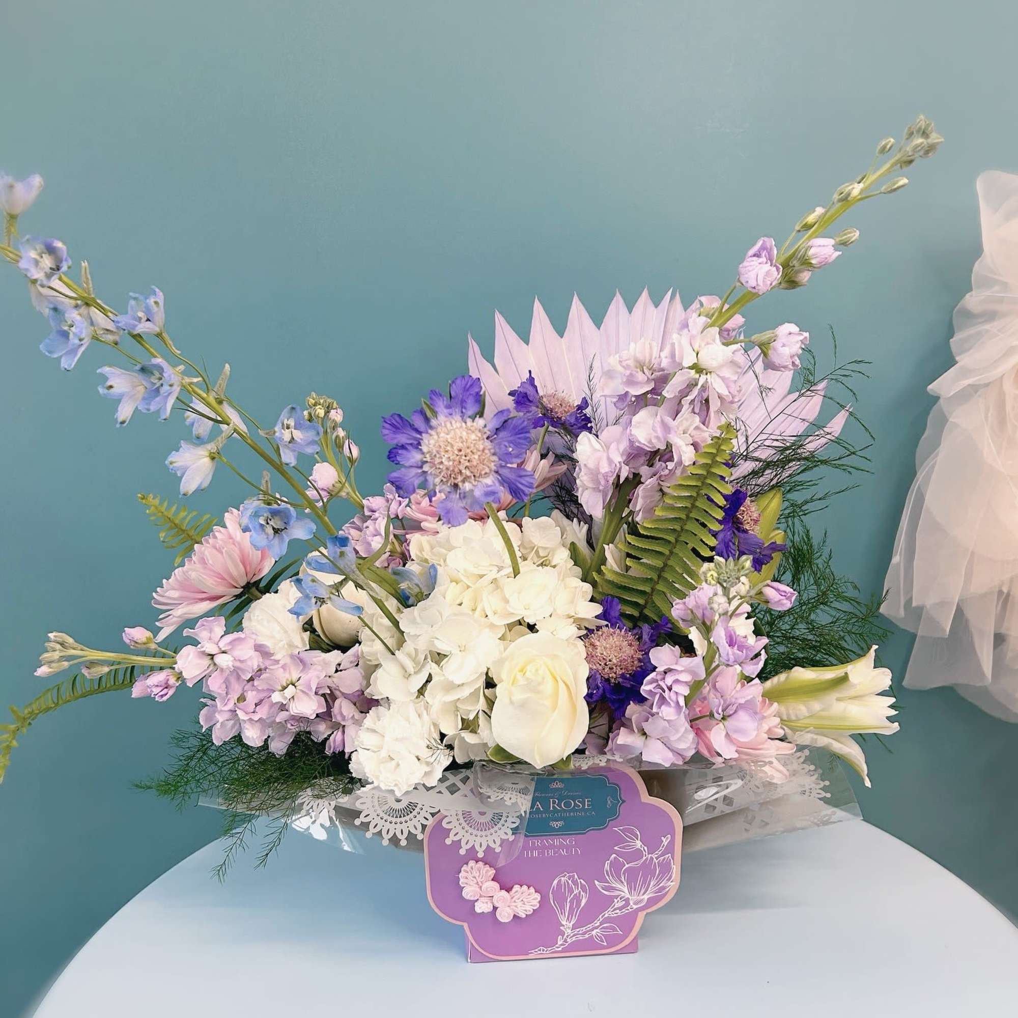 Pastel bouquet with white roses, hydrangea, and lavender flowers in a decorative box