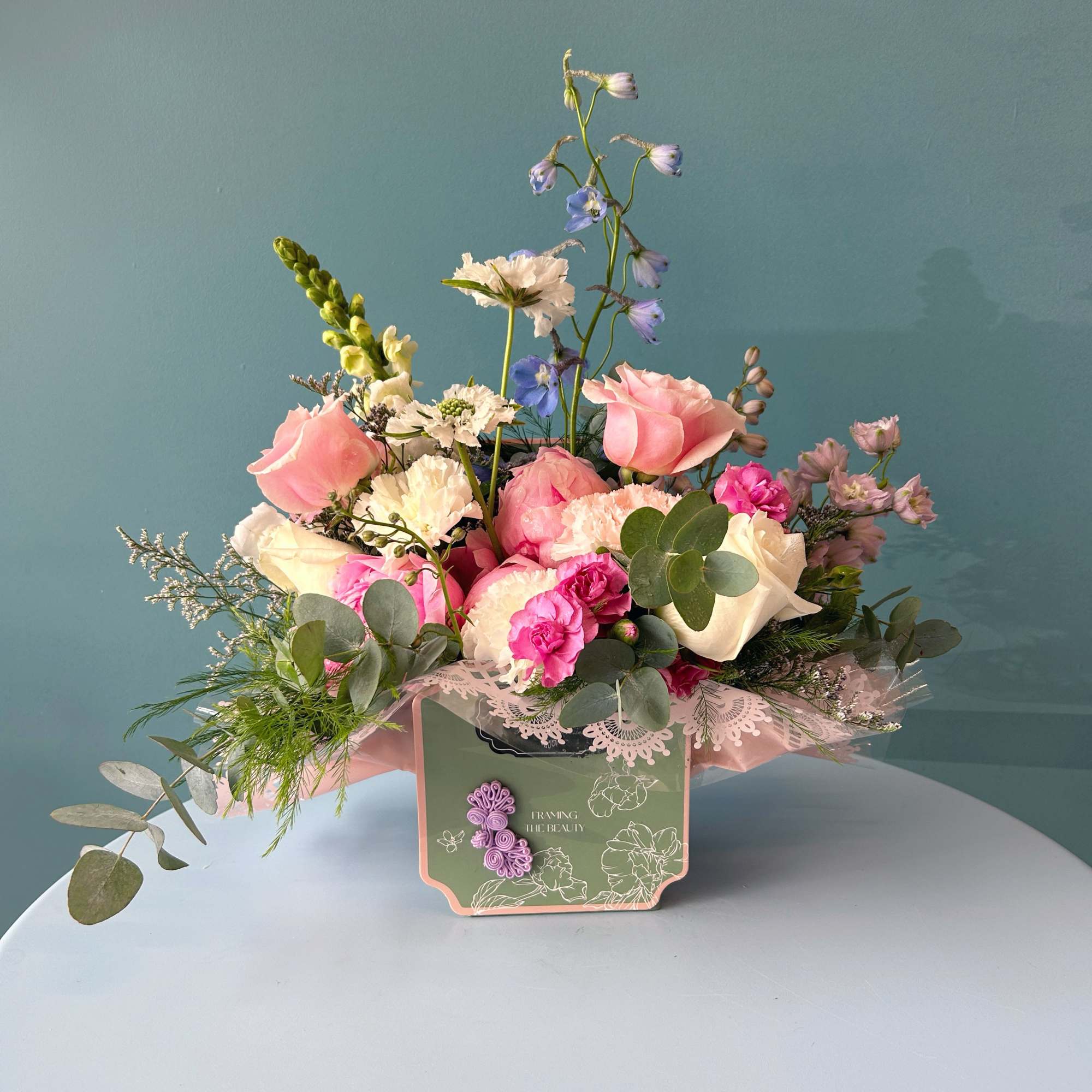 Pink and white mixed flower arrangement in a decorative box