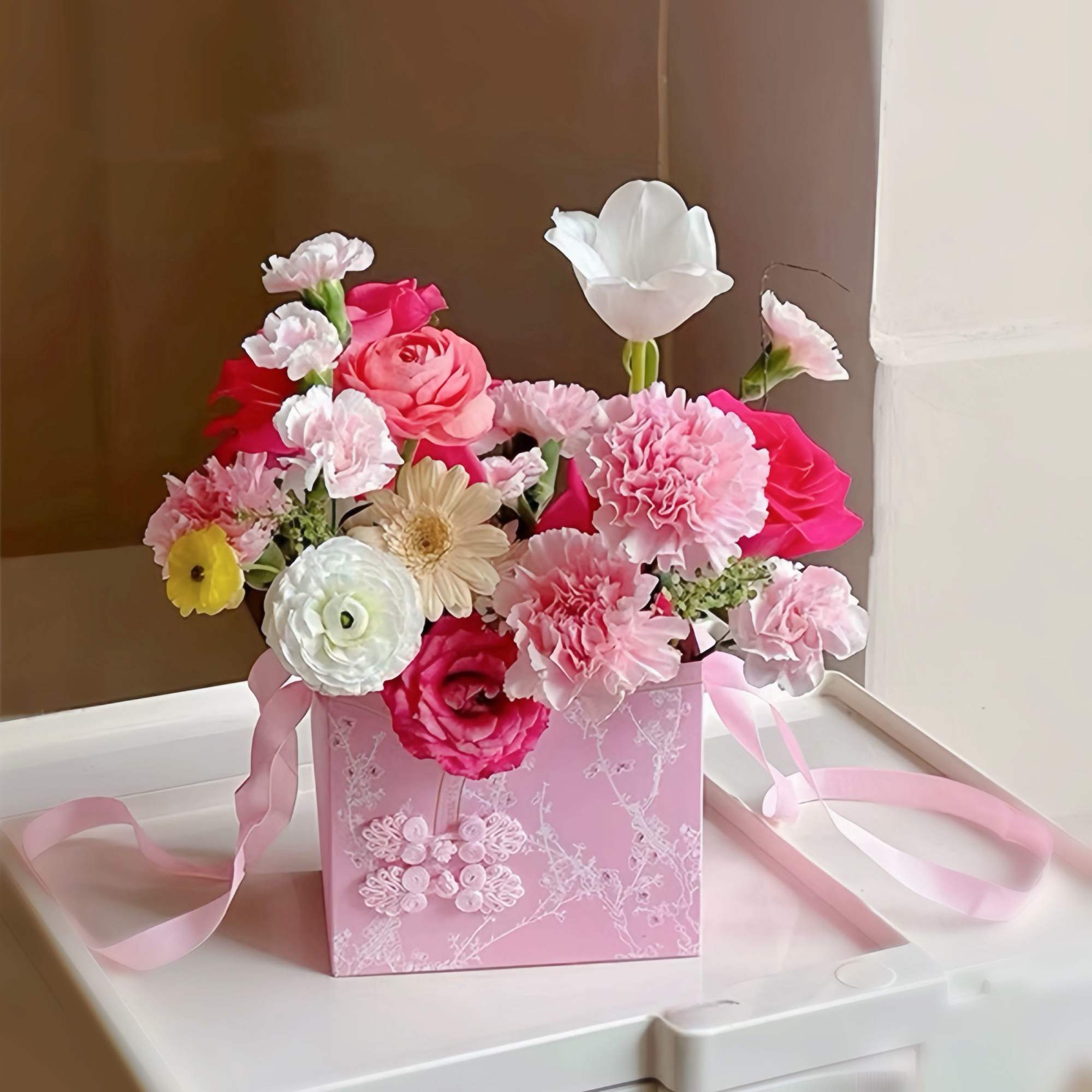 Pink and white mixed flower arrangement in a pink gift box with ribbon