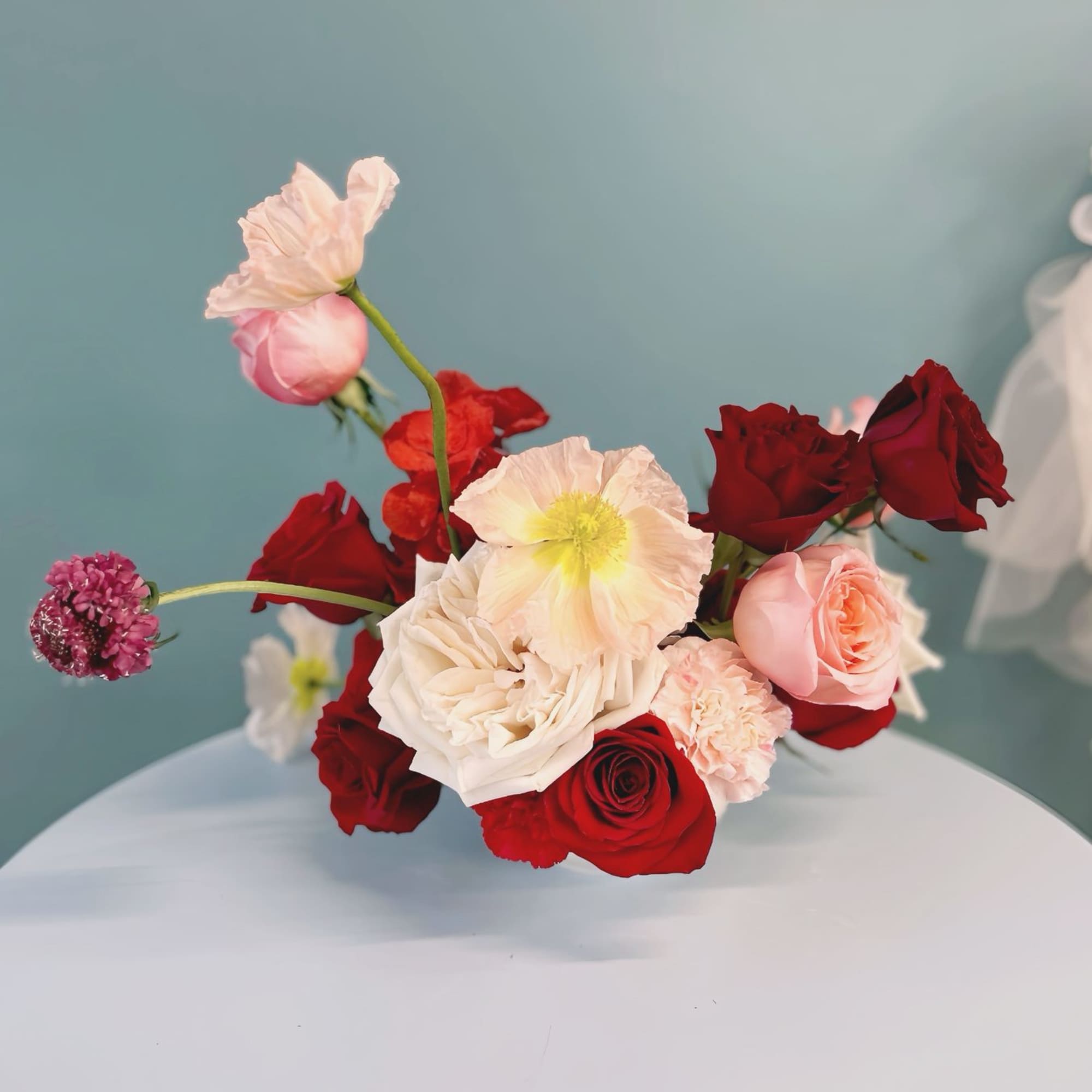 Bouquet of red, blush, and white roses with a few small accent blooms