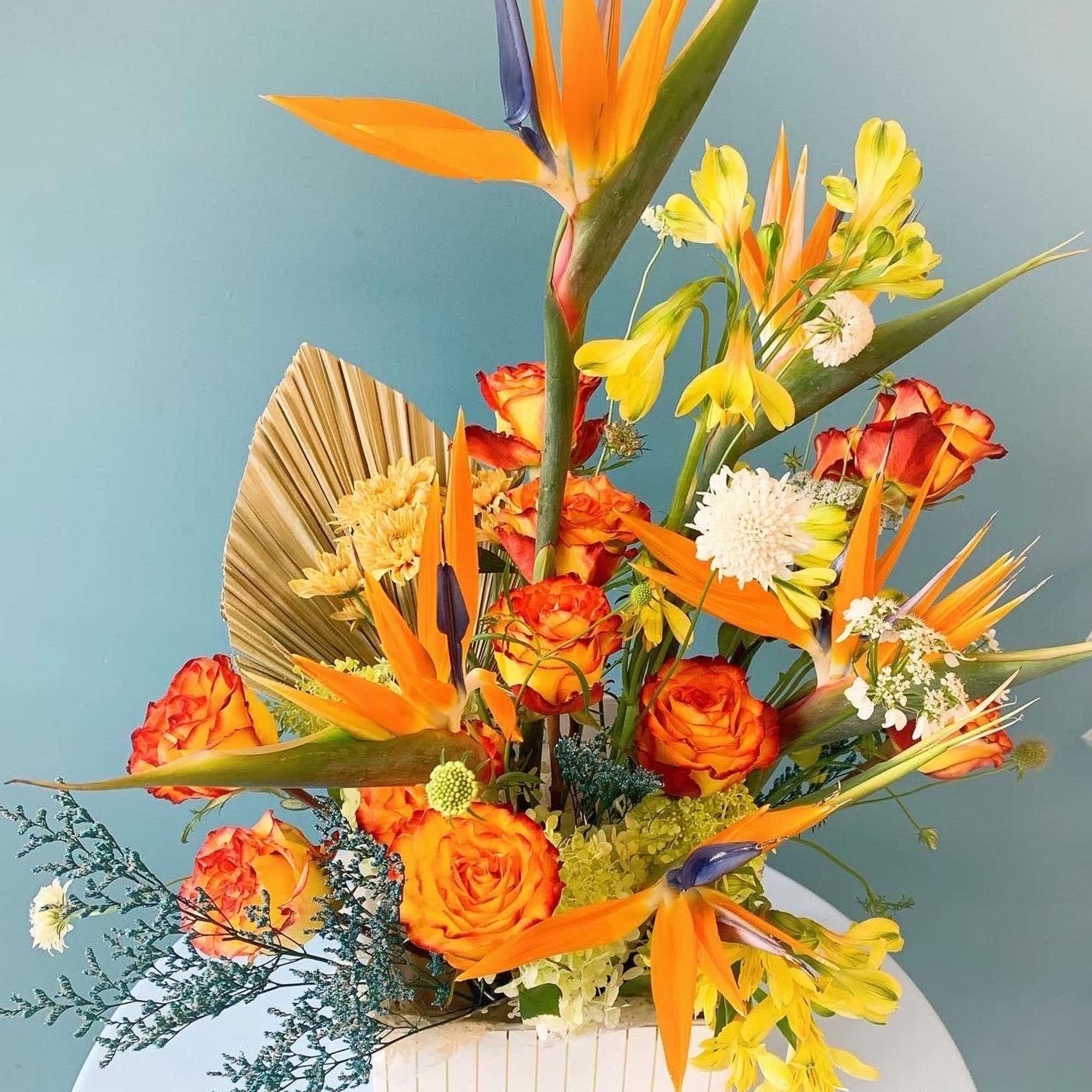 Tropical bouquet with orange roses and bird-of-paradise in a white box