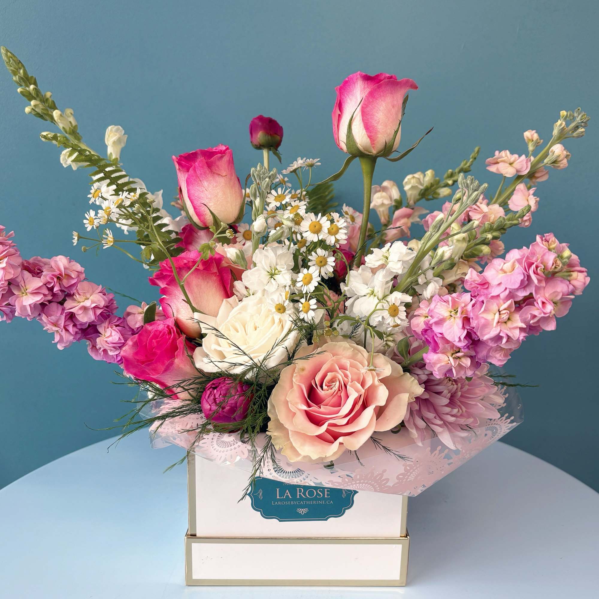 Pink and white rose bouquet in a gift box with small white daisies