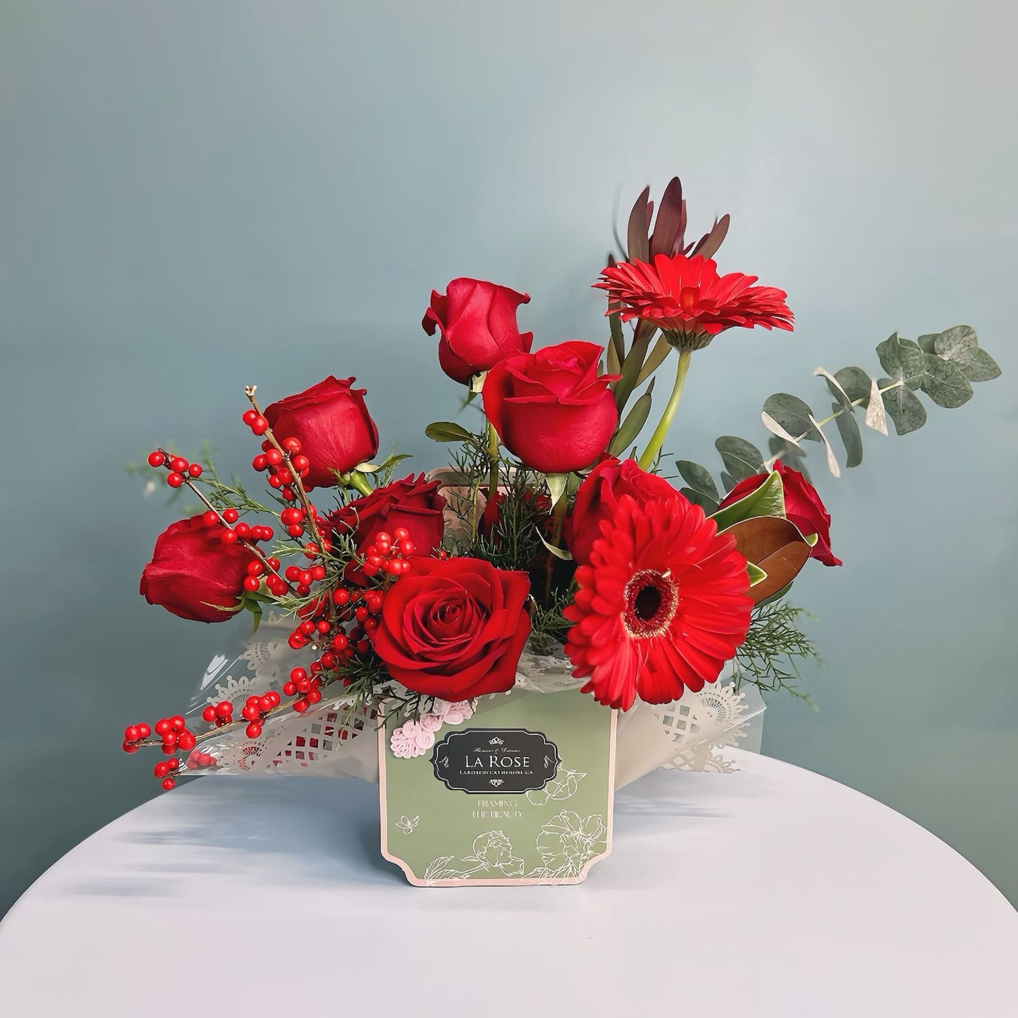 Red roses and gerbera daisies arranged in a decorative box