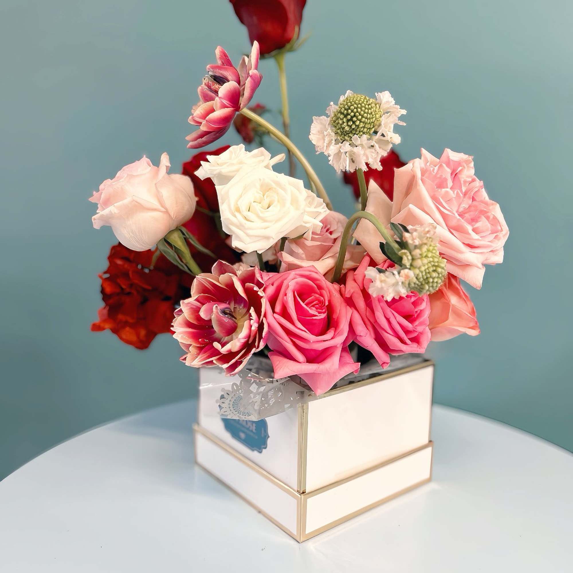 Pink and white roses with red blooms in a square box