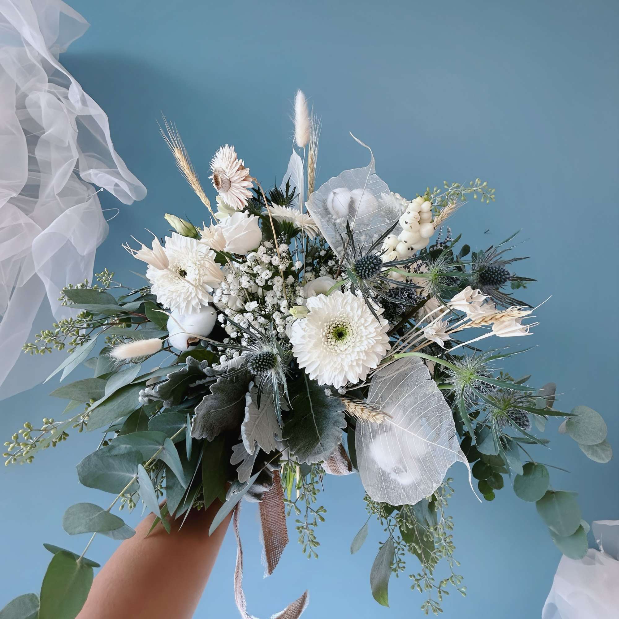 White bridal bouquet with daisies and dried grasses