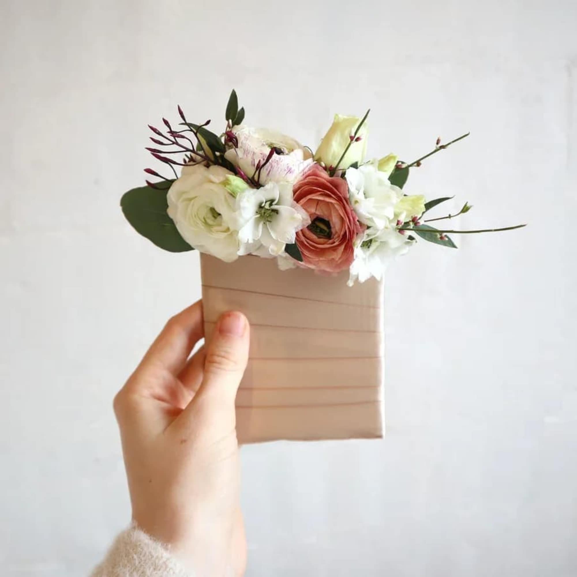 Small hand-tied bouquet of white and peach flowers in a beige wrap