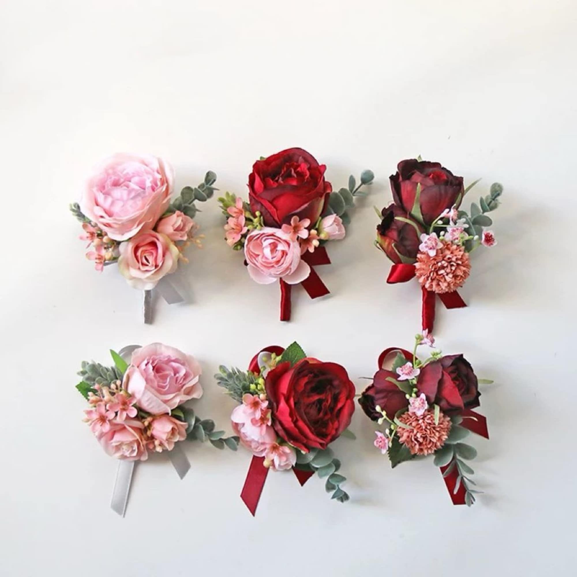 Six small rose boutonnieres in pink and red with ribbon ties