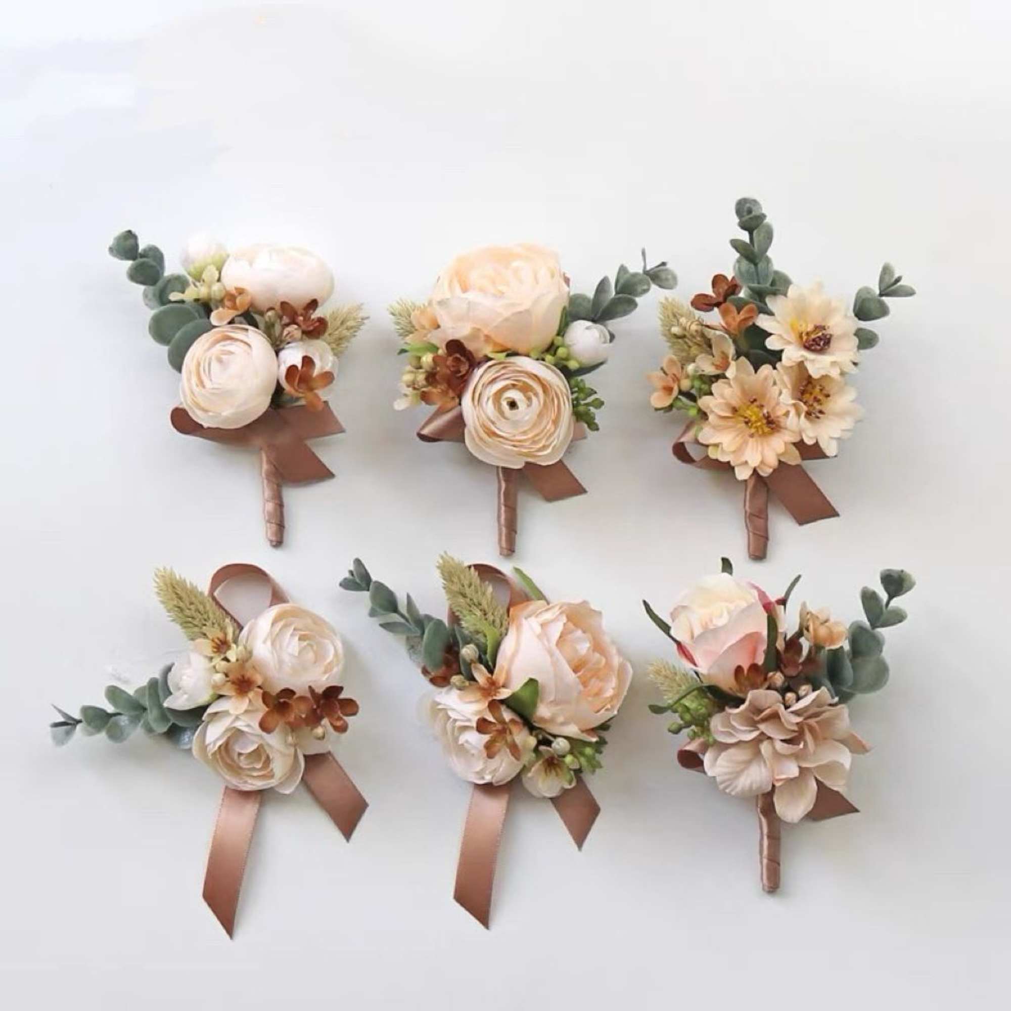 Six small wedding boutonnieres with cream flowers and brown ribbons