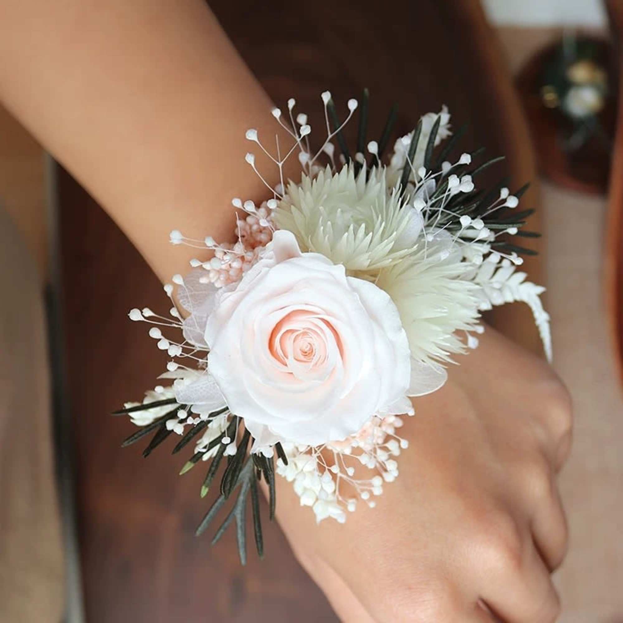 White rose wrist corsage with small filler flowers and dark greenery