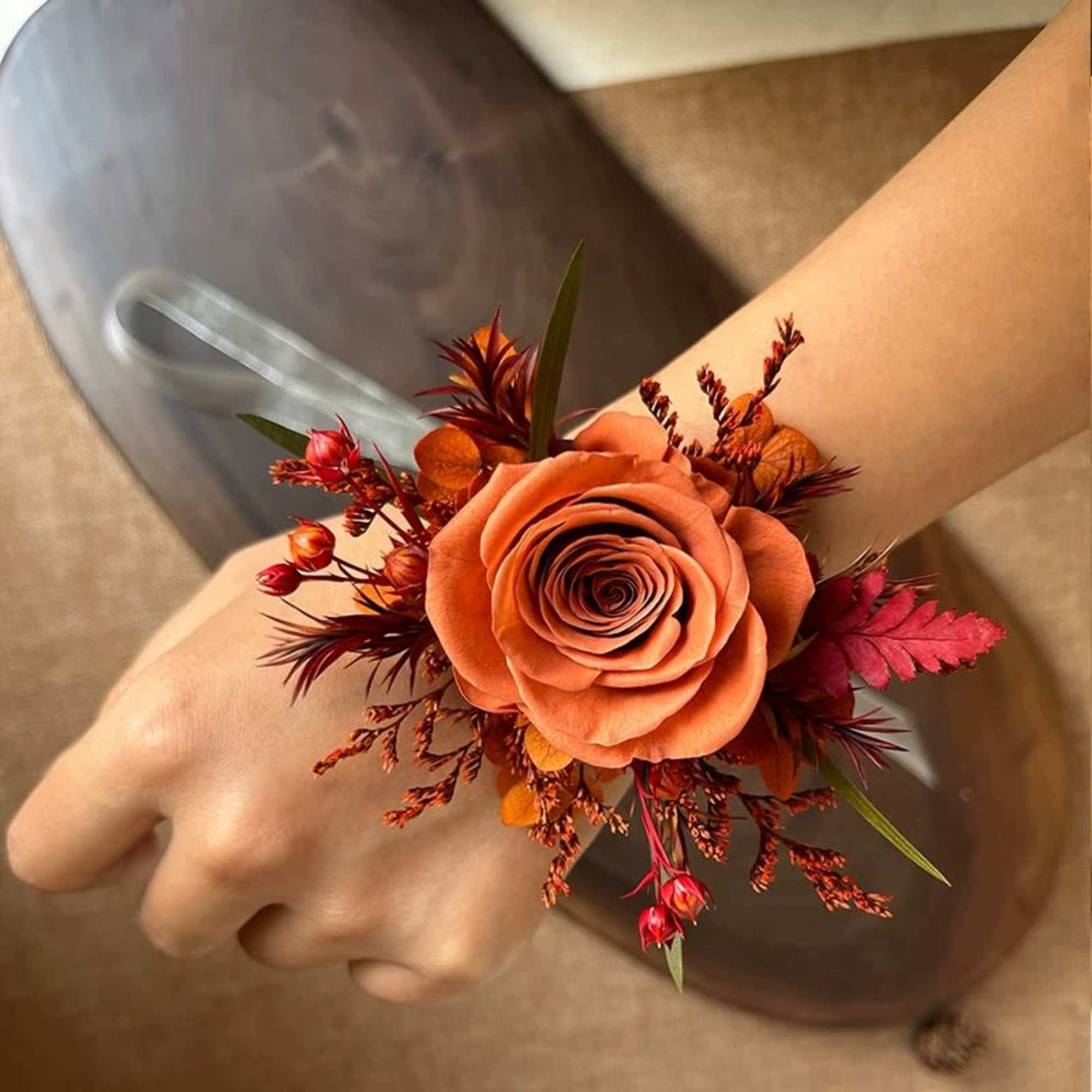 Orange rose wrist corsage with red accents on a wrist
