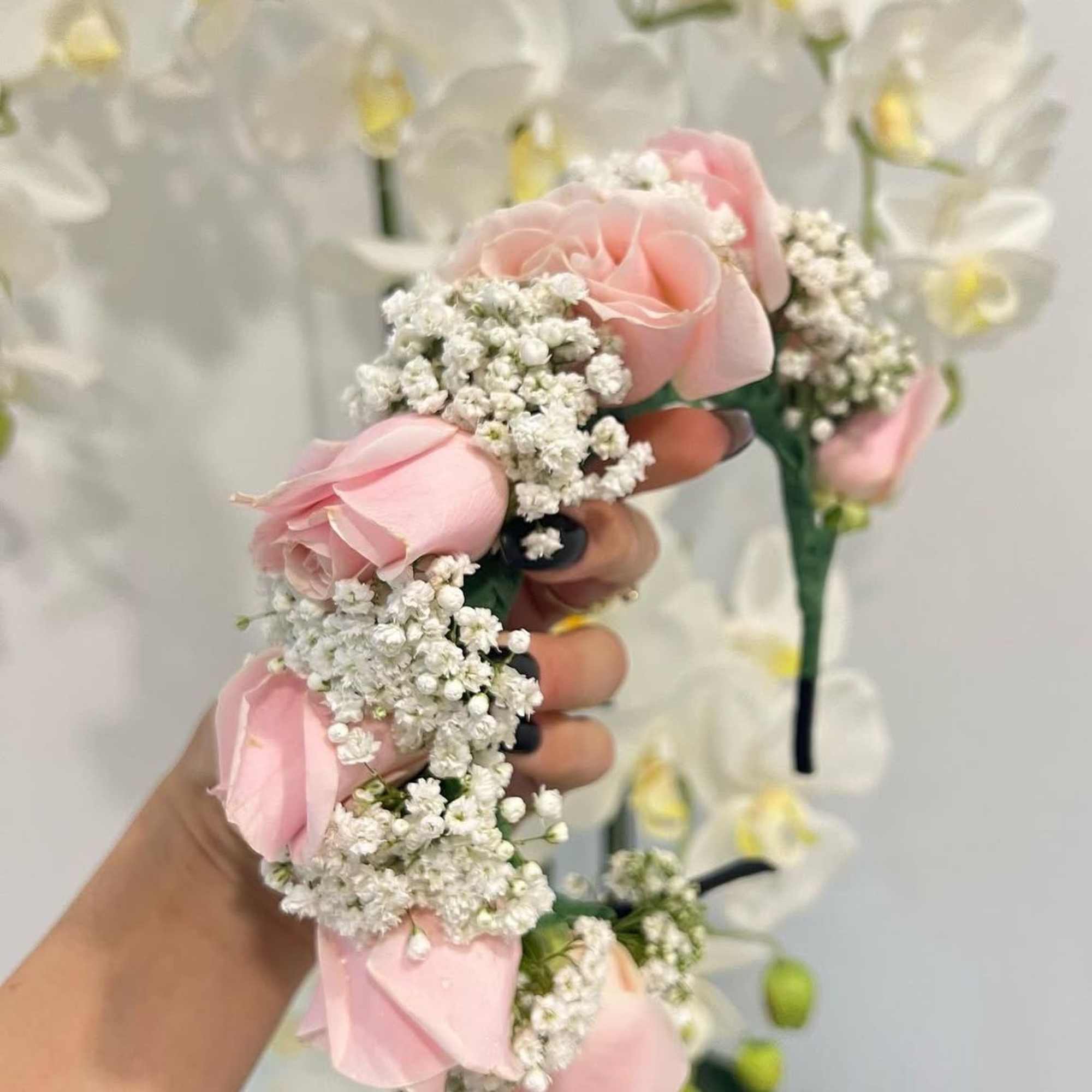 Pink rose and baby's breath floral crown with white orchids in the background