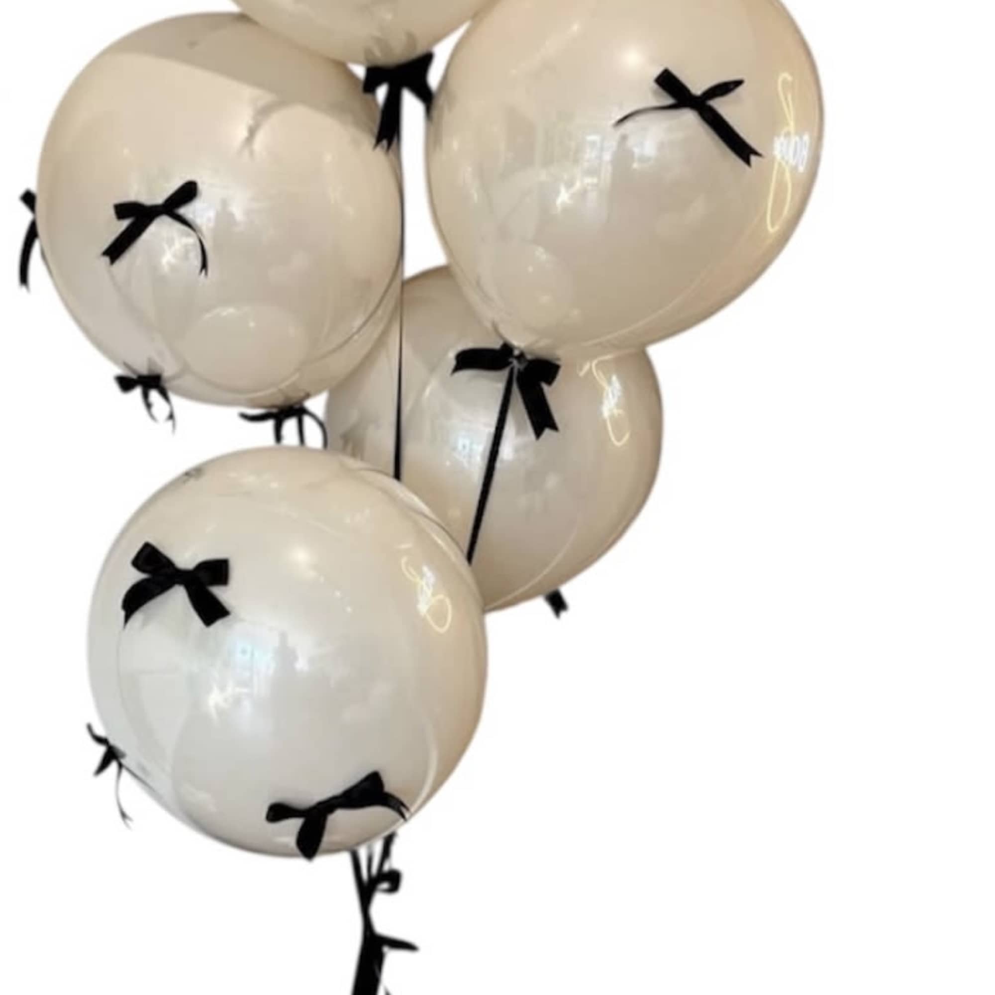 Cluster of cream balloons with black bows and a black ribbon tail