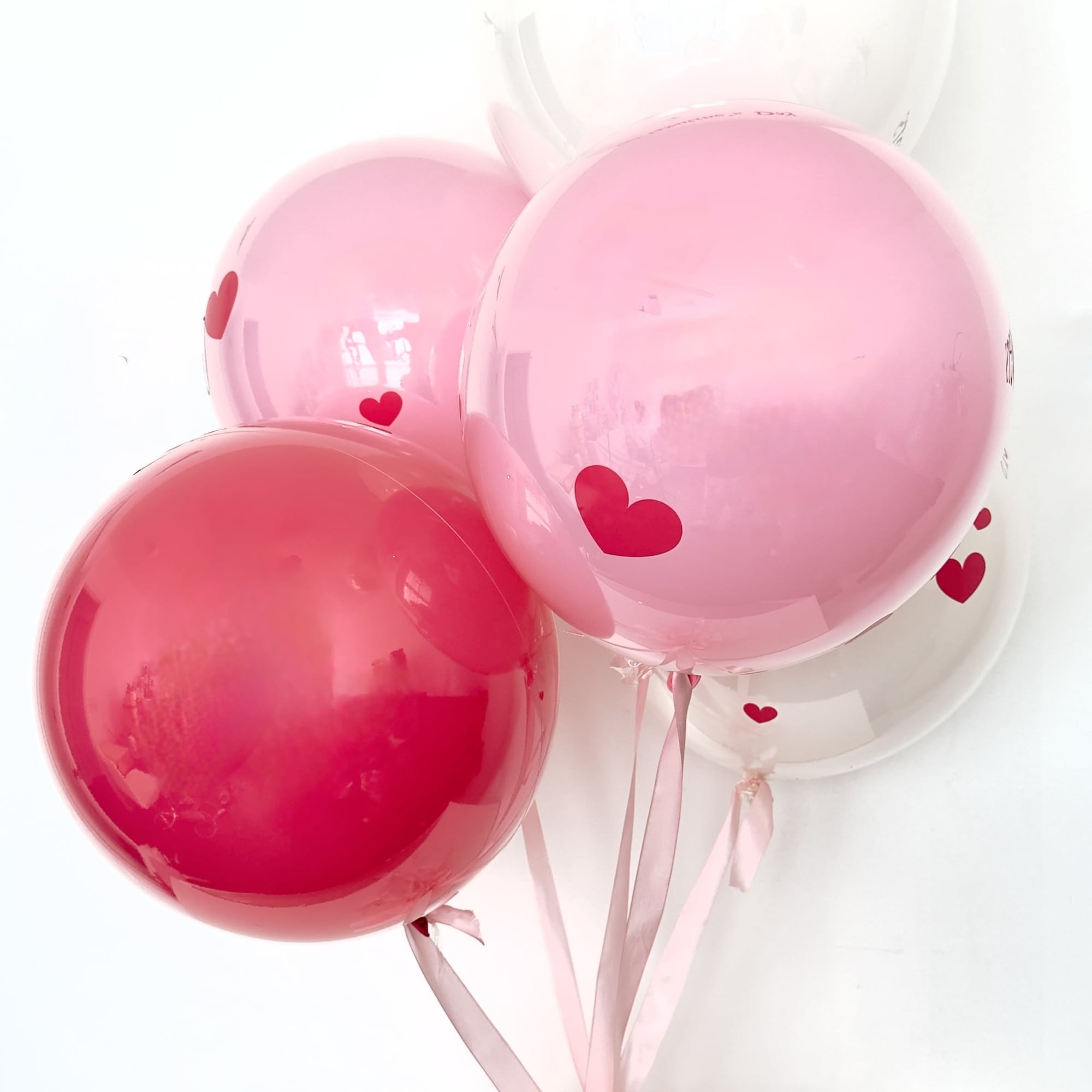 Cluster of pink and white heart balloons with ribbon tails
