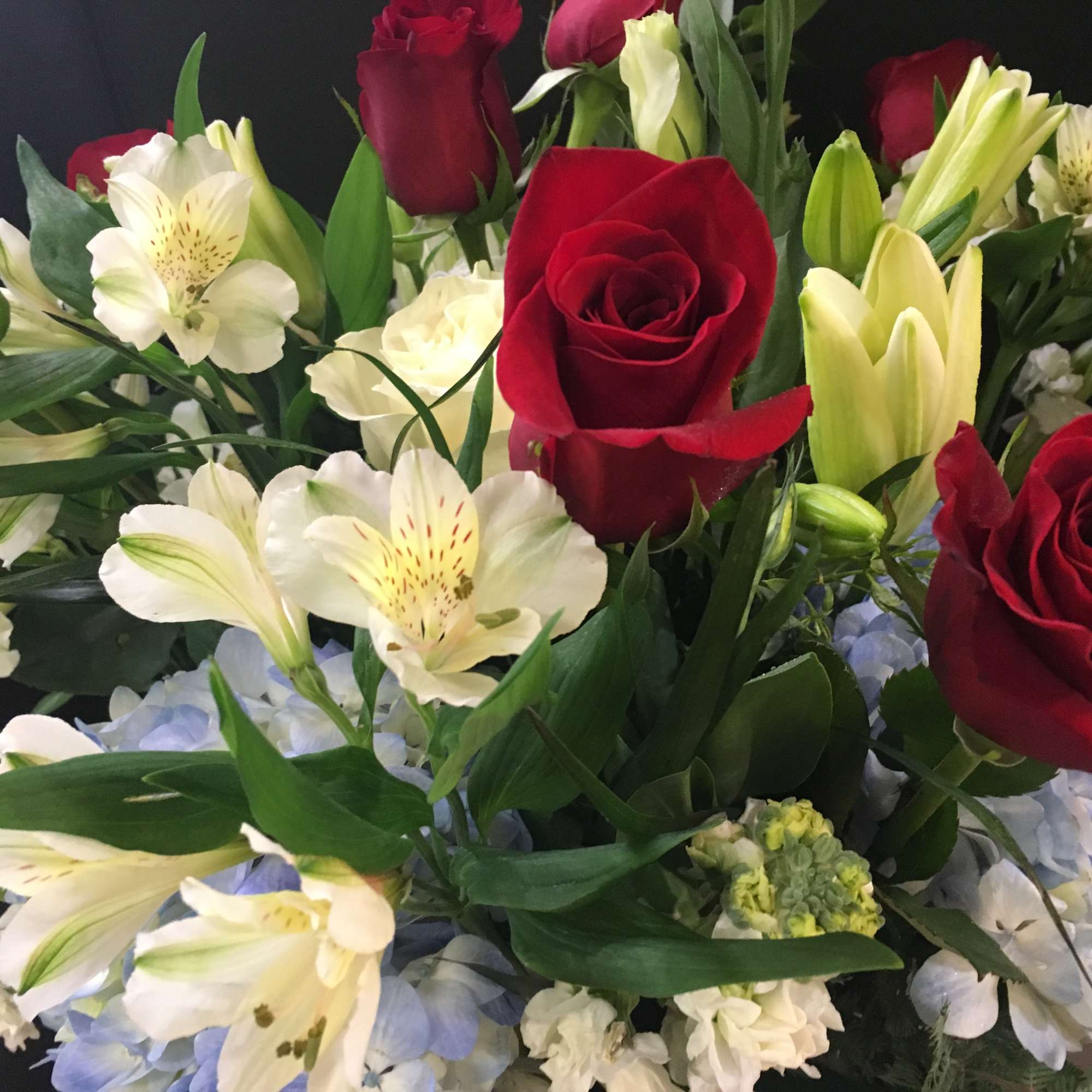 Bouquet of red roses, white lilies, and pale blue hydrangeas