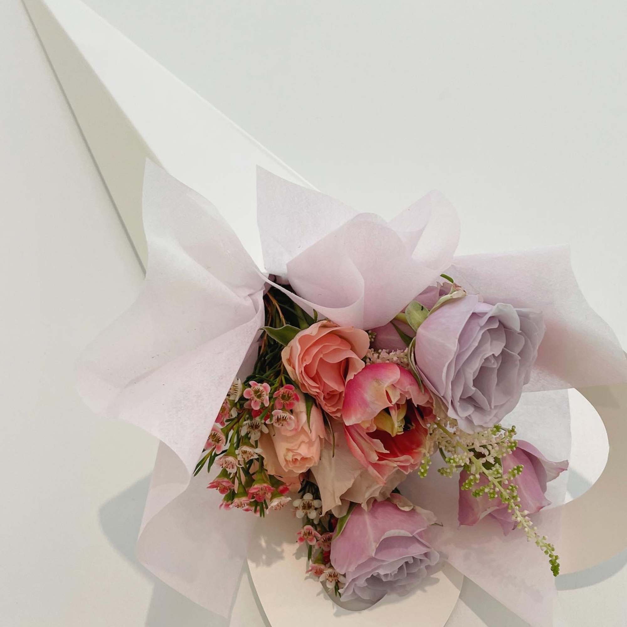 Pastel bouquet with pink and lavender flowers wrapped in white paper