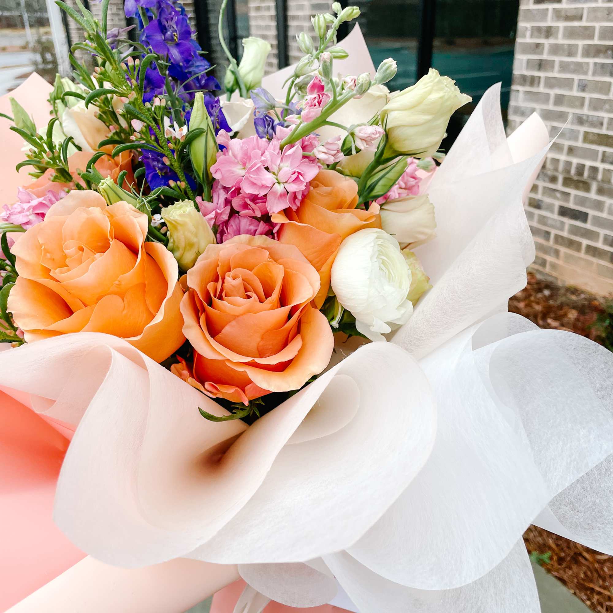 Bouquet of orange and pink roses with purple and white blooms