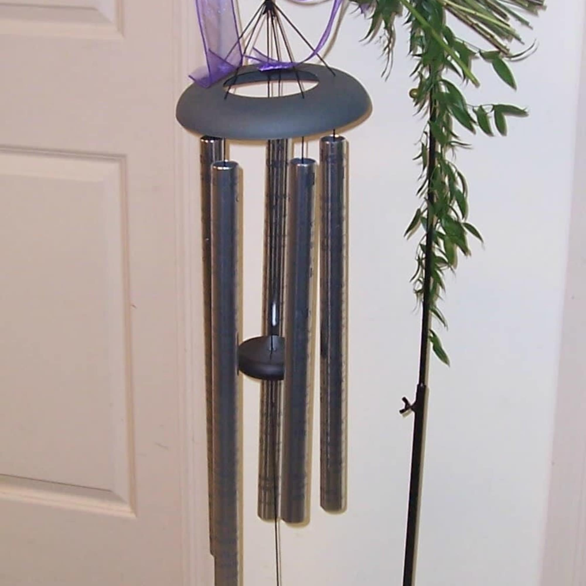 Bouquet of mixed flowers tied with a purple ribbon beside a hanging wind chime