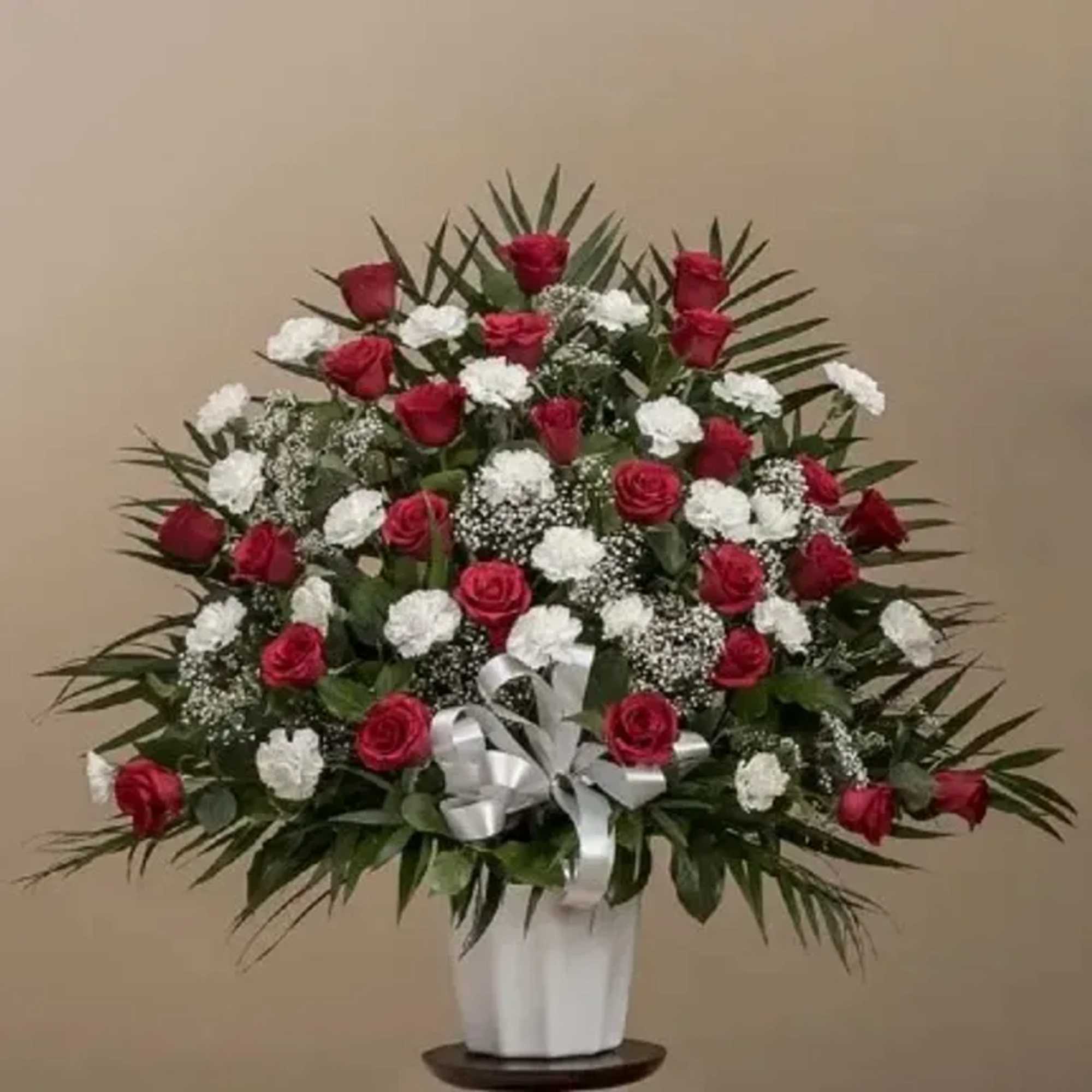A dense, rounded spray of red roses and white carnations creates a