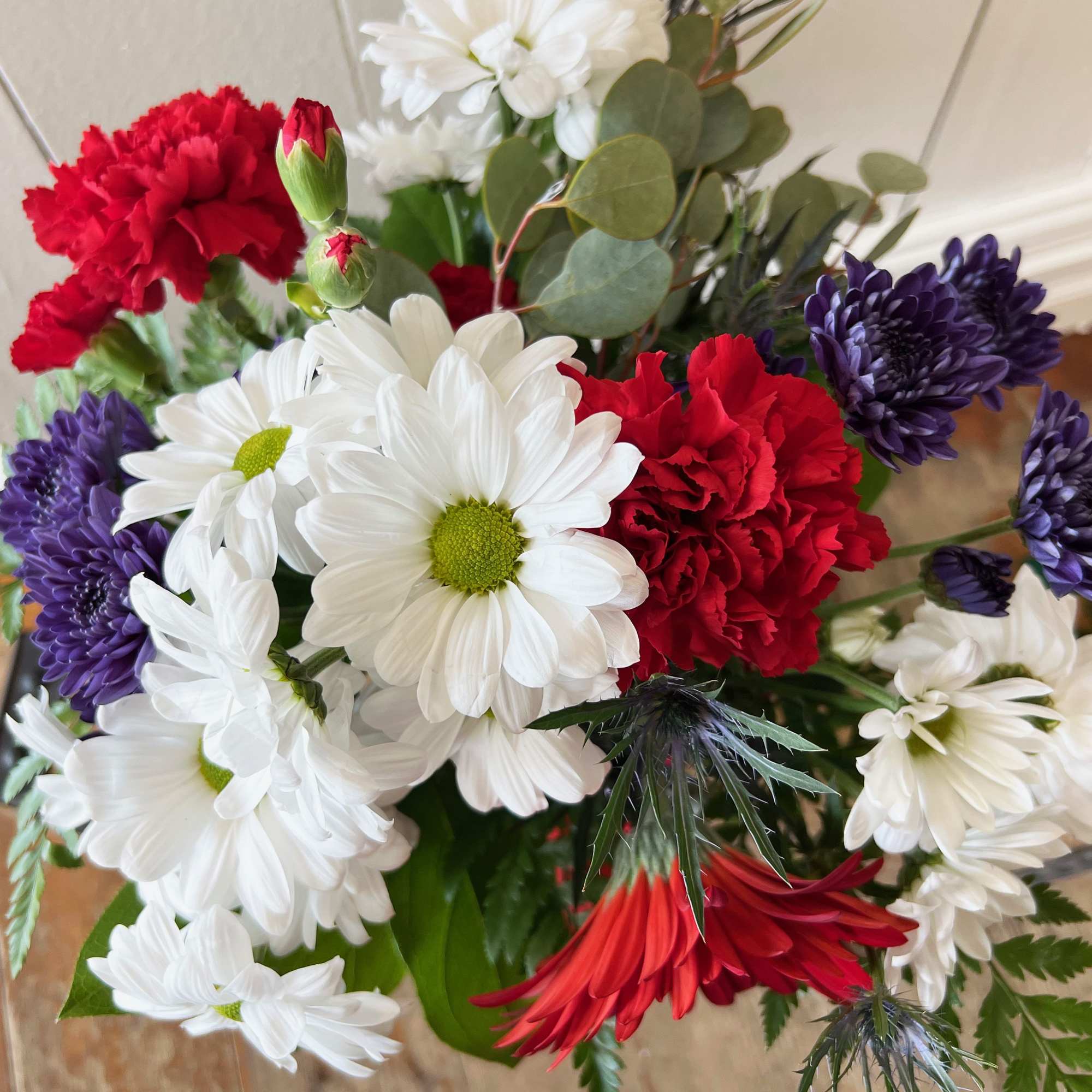 White daisies and vivid red blooms-including carnations and a standout red gerbera-create