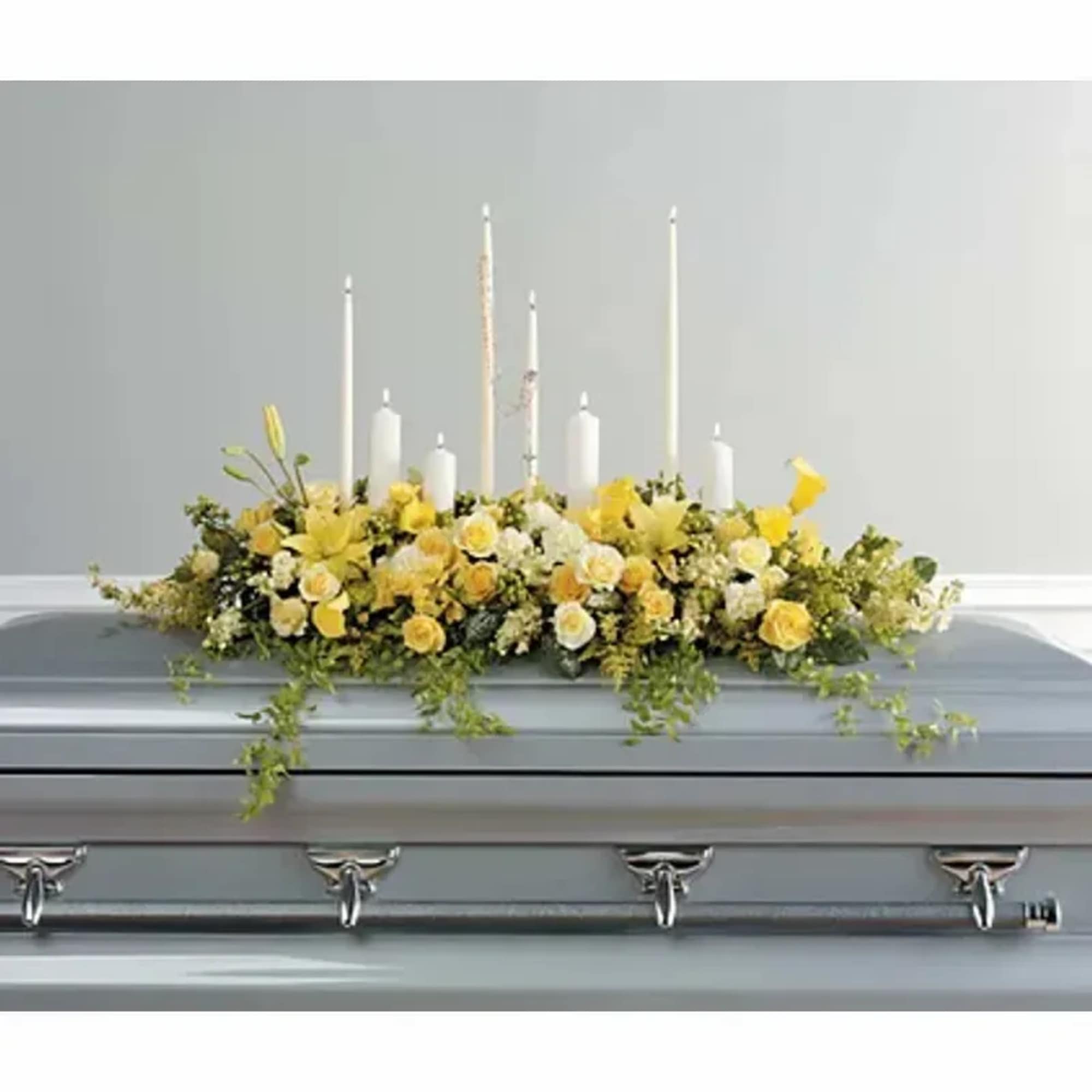 A casket spray in yellow and white. With roses, carnations and lilies.